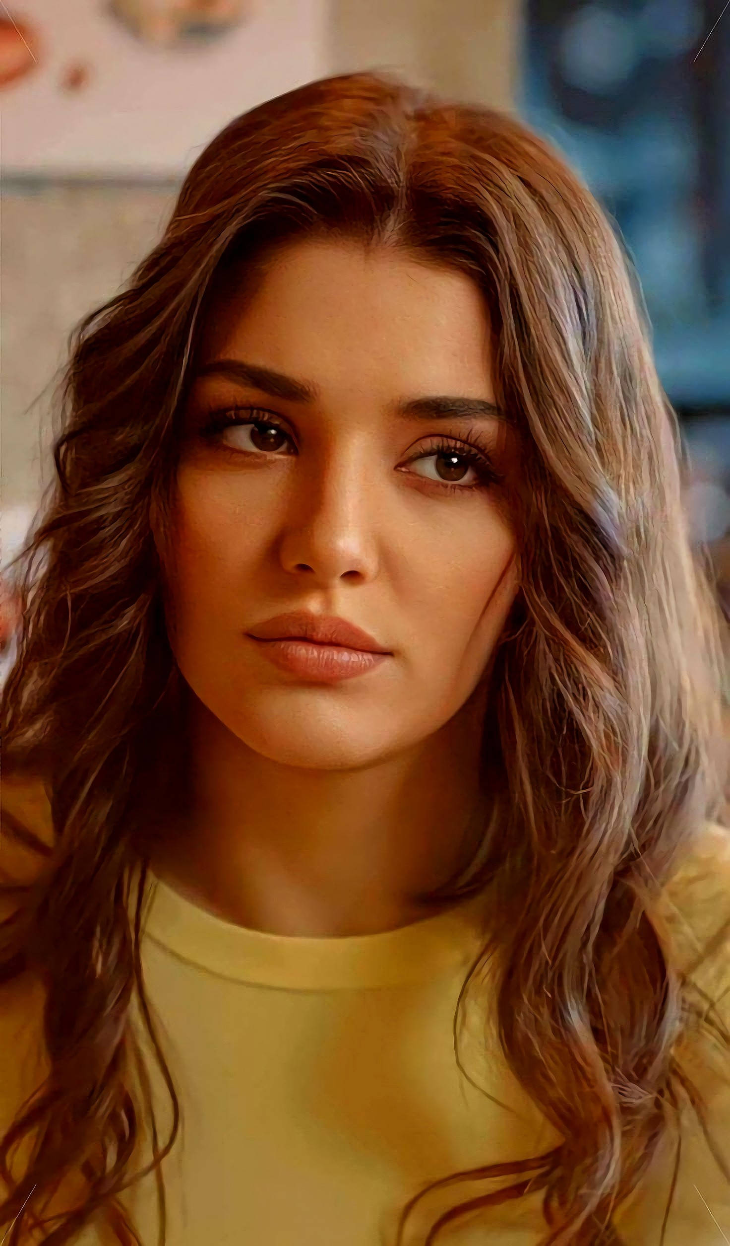 Hande Ercel 長髮造型 壁紙 — 一位擁有波浪棕色頭髮和柔和眼神的女性穿著黃色上衣的特寫肖像。
