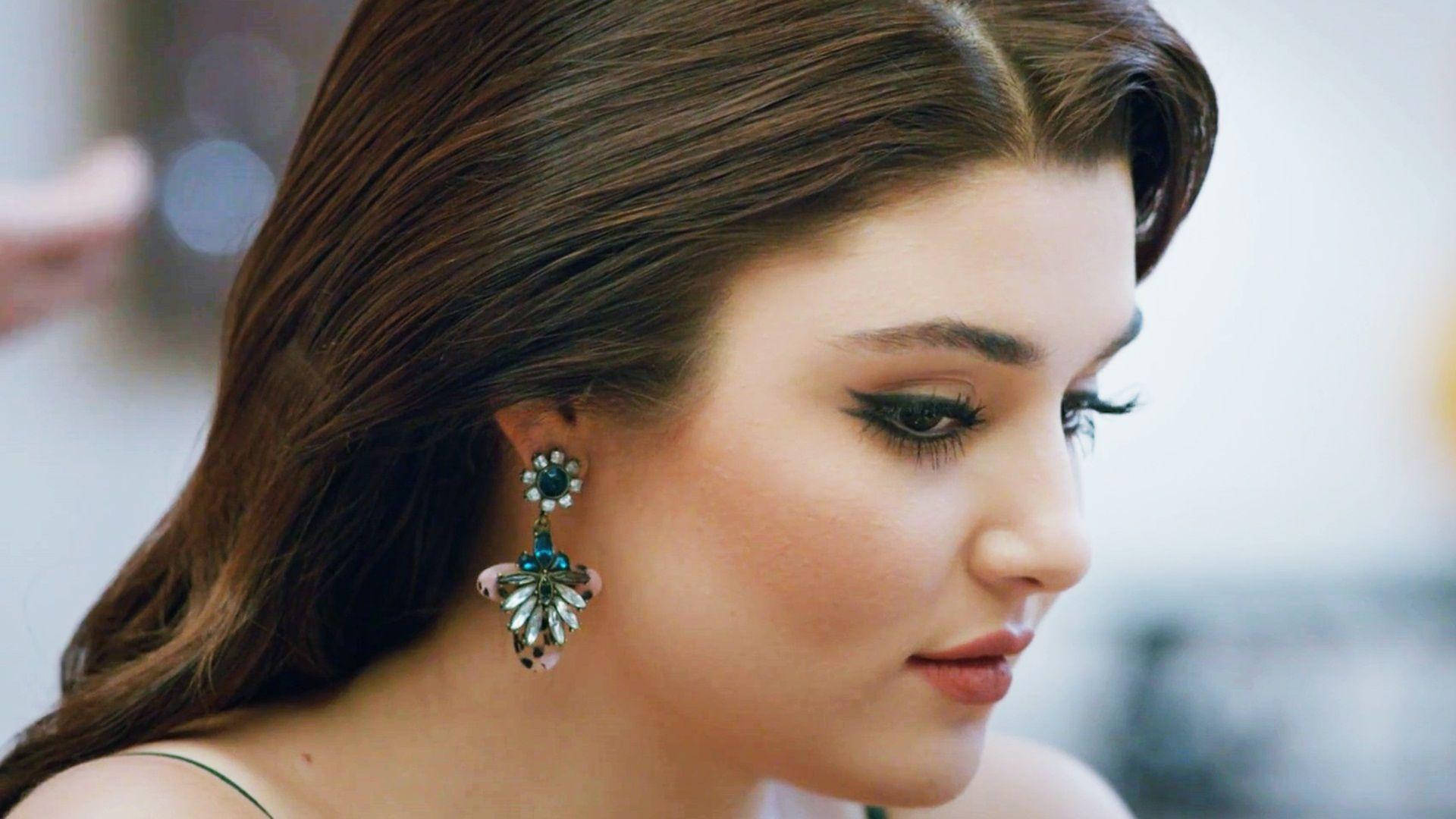 Hande Ercel 美麗近照 壁紙 — 一位長髮棕眼女子佩戴華麗葉形耳環的 close-up 肖像，目光向下，背景柔和模糊。