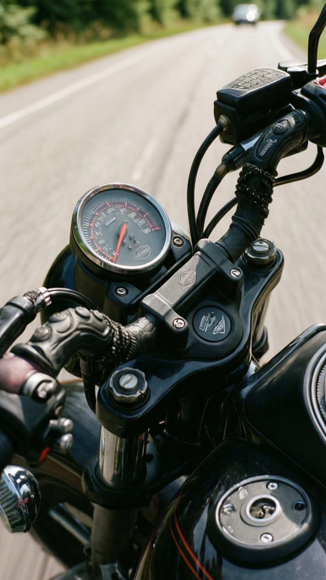 Handlebars in Motion 壁紙 — 電單車的把手和速度計在陽光明媚的鄉村道路上飛馳的特寫。