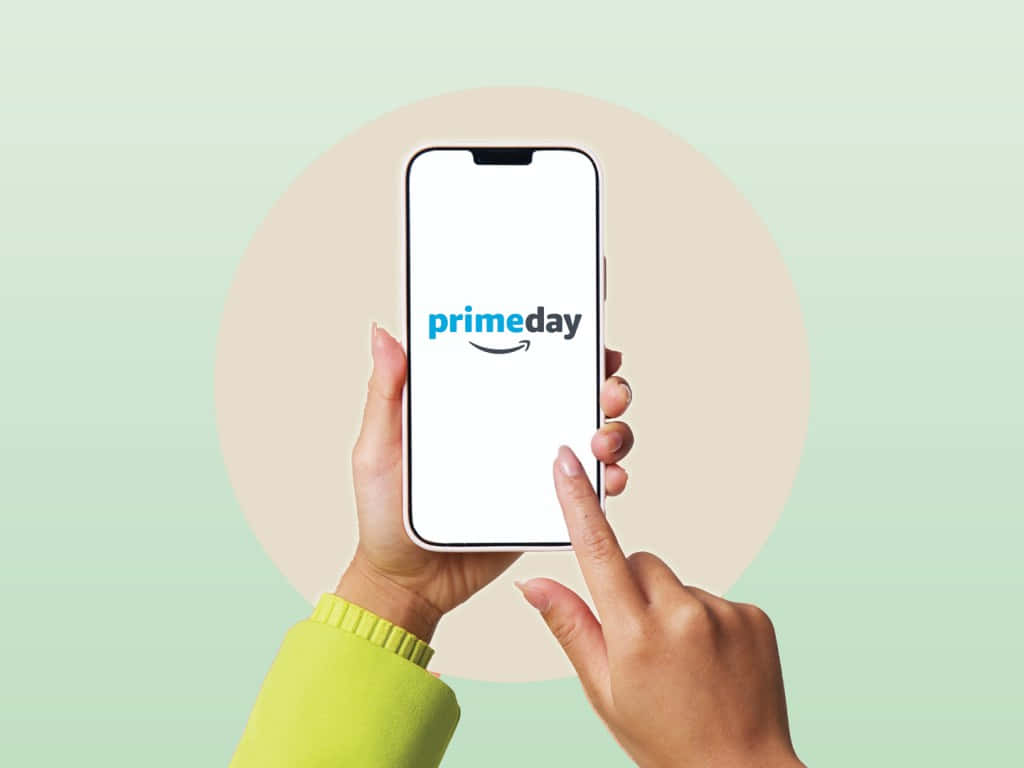  壁紙 — 雙手拿著一部智能手機，屏幕上顯示 Prime Day 標誌，背景是柔和粉彩色。