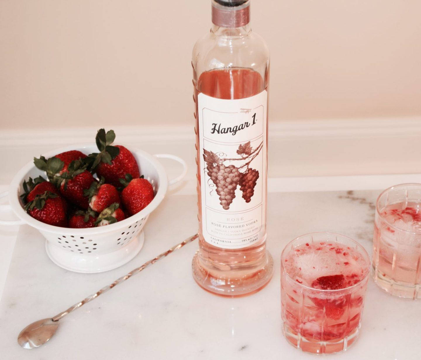 Hangar 1 茉莉珍珠伏特加混合 壁紙 — 一瓶Hangar 1 Rosé Vodka與新鮮草莓和兩杯草莓雞尾酒放在大理石檯面上。