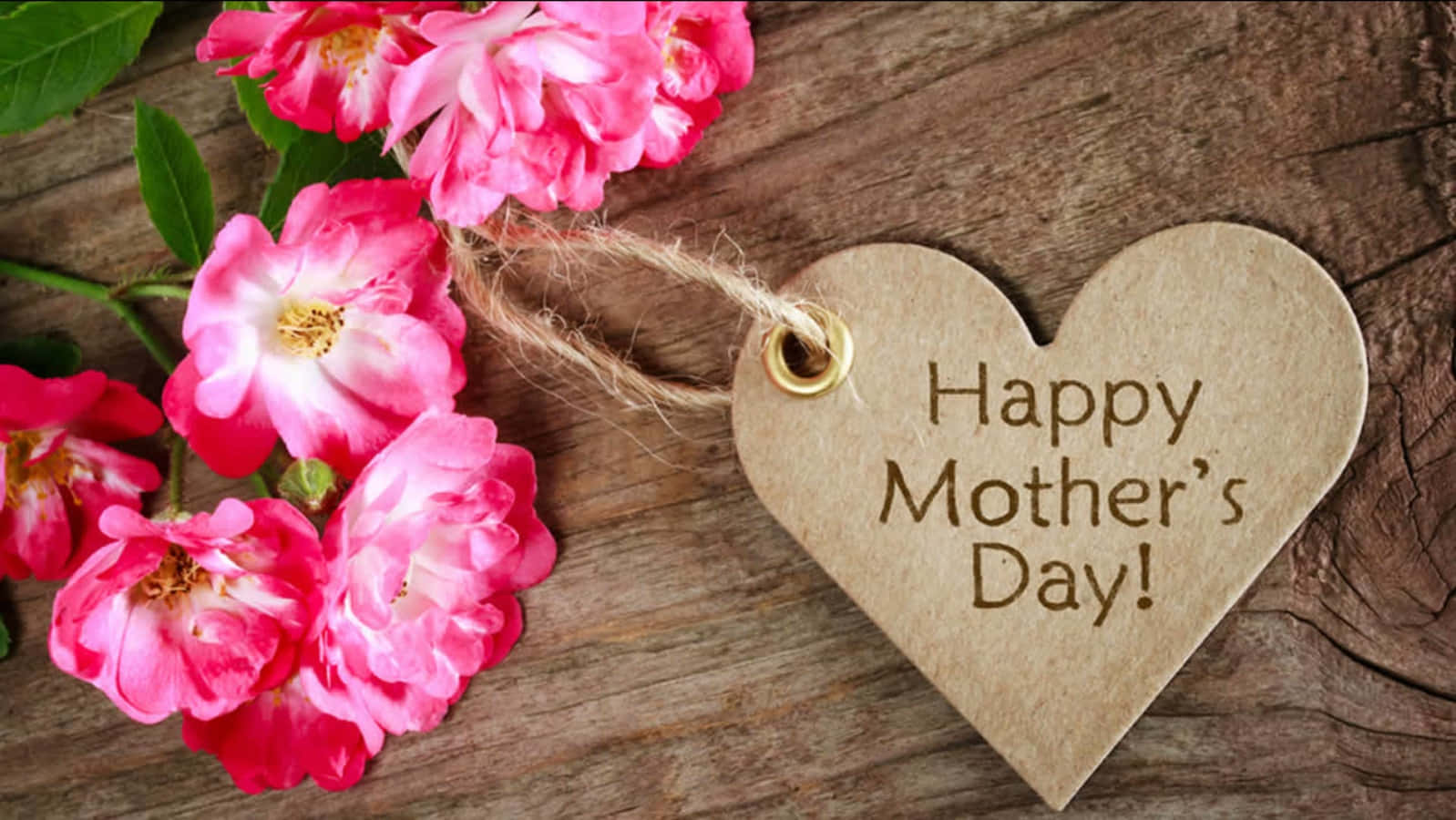 粉紅玫瑰和一個帶有「Happy Mother's Day」訊息的木製心形標籤在木頭上。