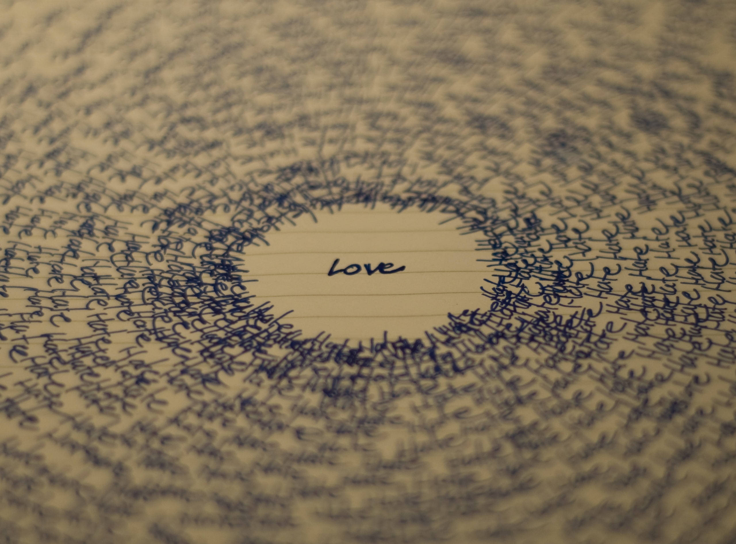 Hate Love 隨筆 壁紙 — 手寫字詞從中央的「愛」向外輻射的特寫，寫在橫線紙上，景深較淺。