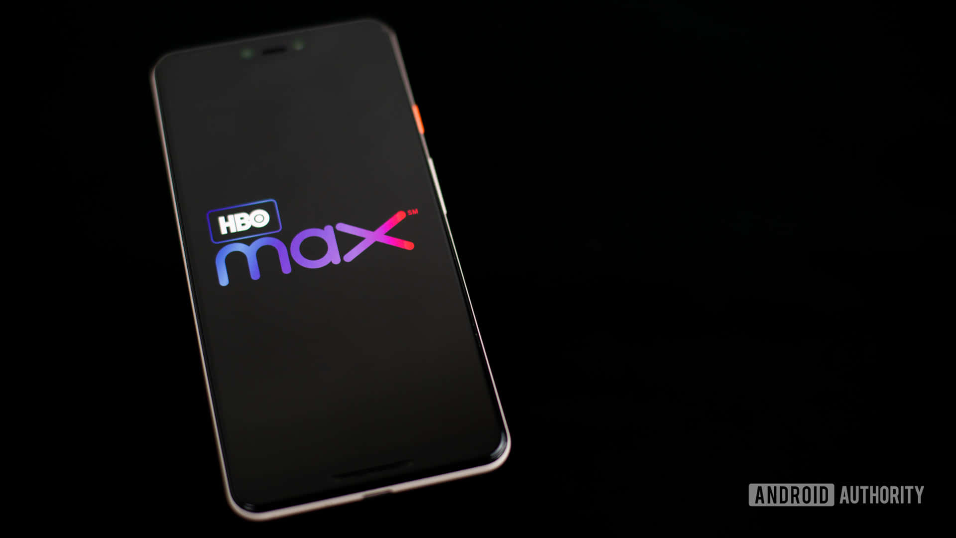 智能手機在暗色屏幕上顯示HBO Max標誌，帶有柔和光線。