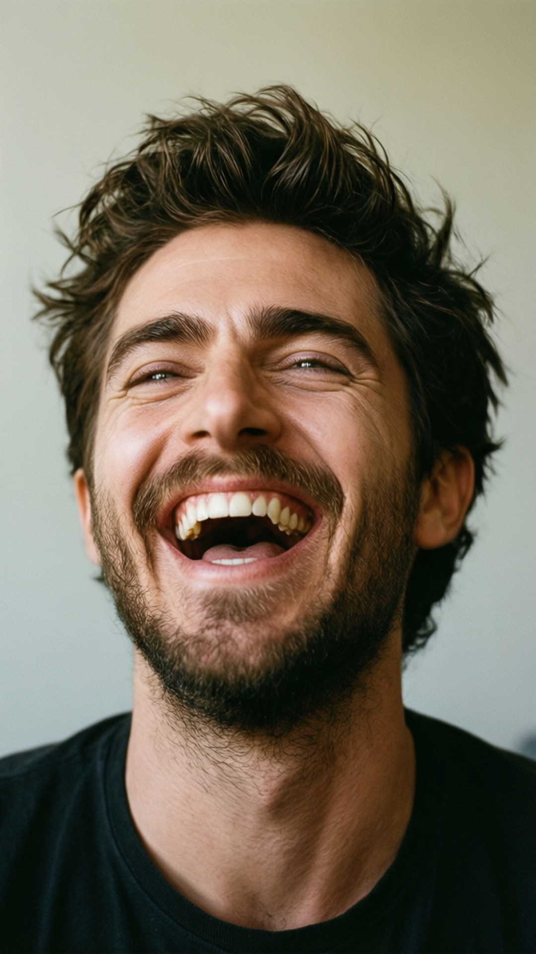 一個黑髮留鬍的男人在特寫鏡頭中開心地笑著。