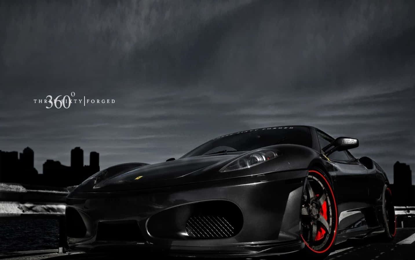 Ferrari 360 Modena 桌布 壁紙 — 一輛時尚的黑色法拉利跑車，帶有紅色制動卡鉗，停在潮濕的道路上，背景是暴風雨的天空和城市天際線。