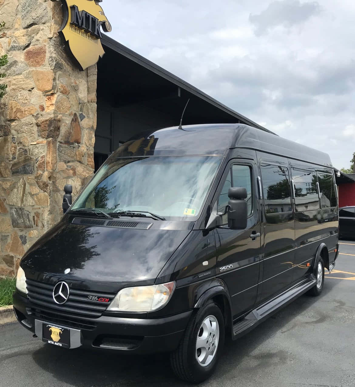 Mercedes Benz Sprinter 桌布 壁紙 — 一架時尚的黑色 Mercedes-Benz Sprinter 客貨車停泊在石建築物外，天空多雲。