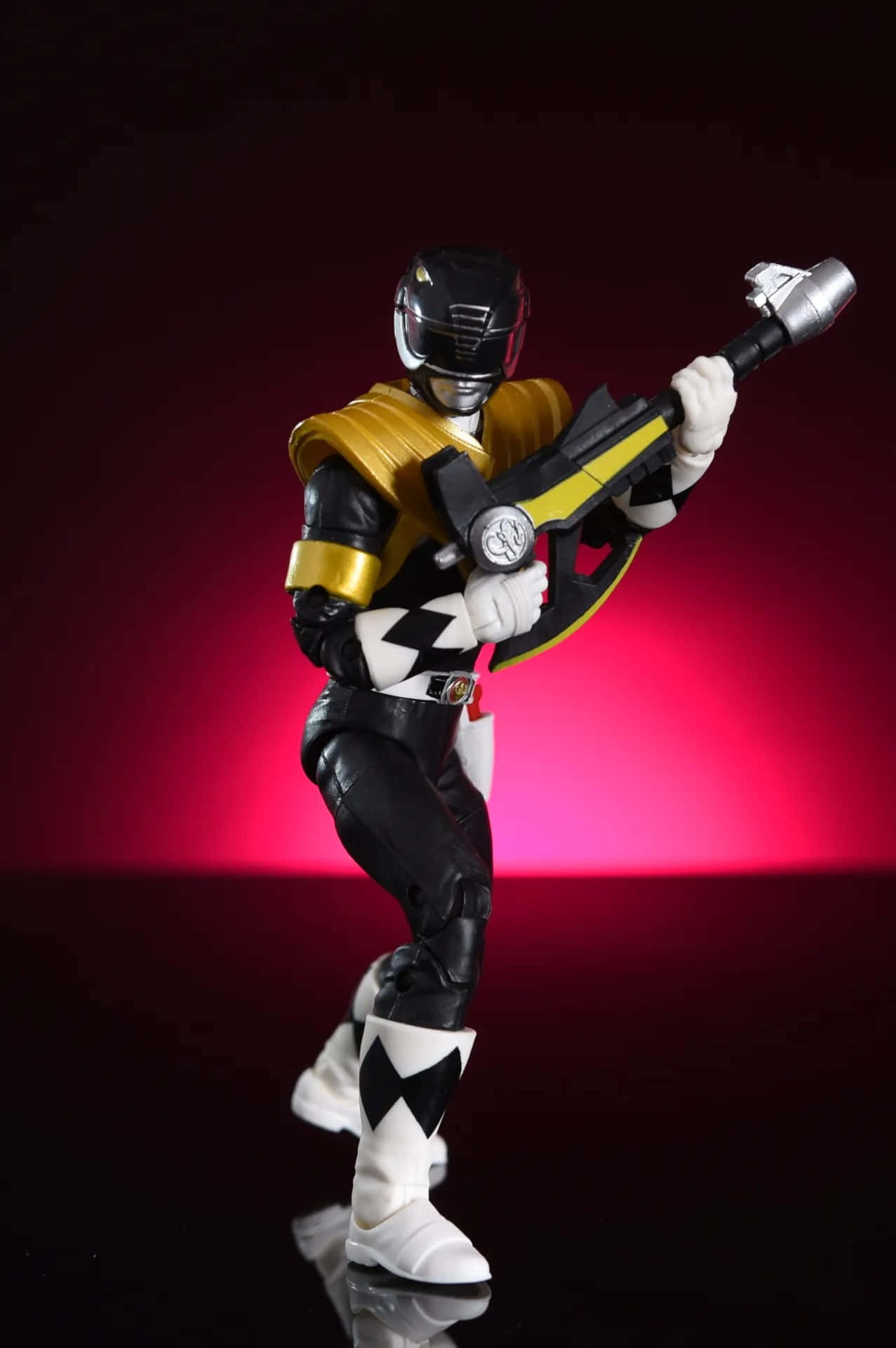  壁紙 — 一個黑色和金色的Power Ranger動作人偶在發光的紅色背景下動態地擺姿勢，手持武器。