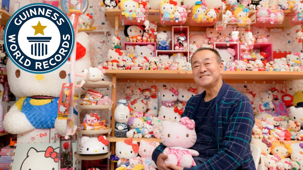 Hello Kitty 喜愛為特別場合打扮 壁紙 — 一位微笑的男子抱著Hello Kitty毛絨玩具，周圍是擺滿色彩繽紛Hello Kitty商品的架子，這是一個健力士世界紀錄認證的收藏。