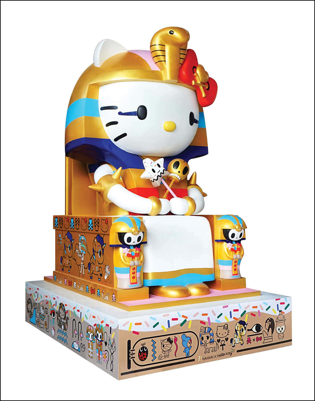 Hello Kitty 始終可愛又開心 壁紙 — Hello Kitty 身穿金色法老服裝，坐在裝飾華麗的基座上，手持骷髏權杖。