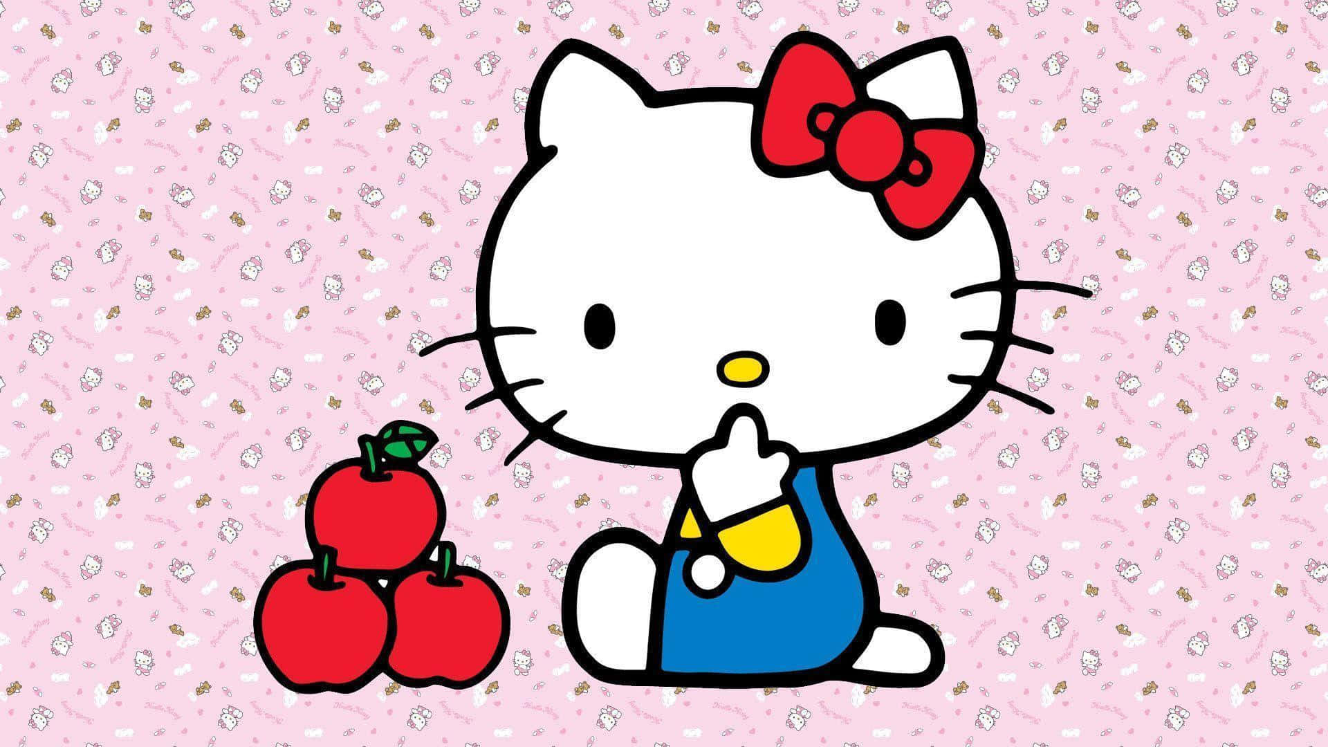 Hello Kitty 旁坐蘋果背景 壁紙 — Hello Kitty 身穿藍色工裝褲，坐在粉紅色圖案背景上的三個紅蘋果旁邊。