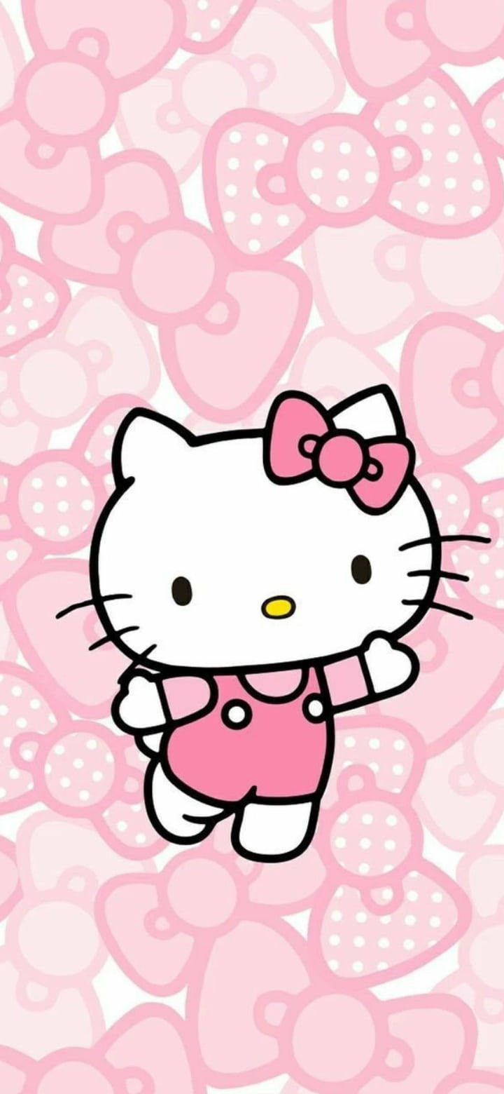 Hello Kitty 卡通角色身穿粉紅色工人褲，在粉紅色蝴蝶結背景前揮手。 — Hello kitty 美學 GIF 壁紙