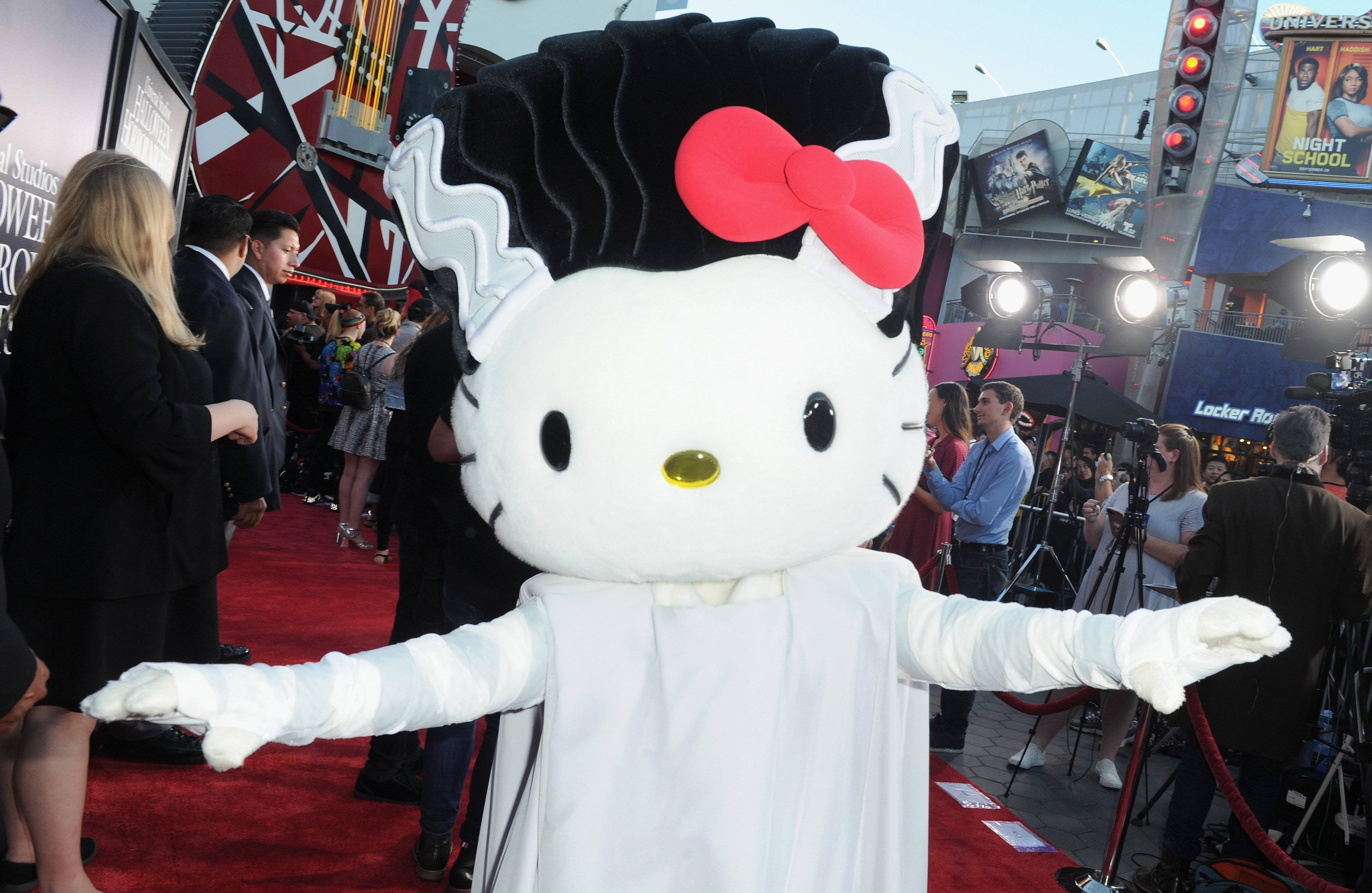 Hello Kitty萬聖節木乃伊造型 壁紙 — 一個穿著新娘裝、黑髮紅蝴蝶結的Hello Kitty吉祥物站在荷里活活動的紅地毯上。