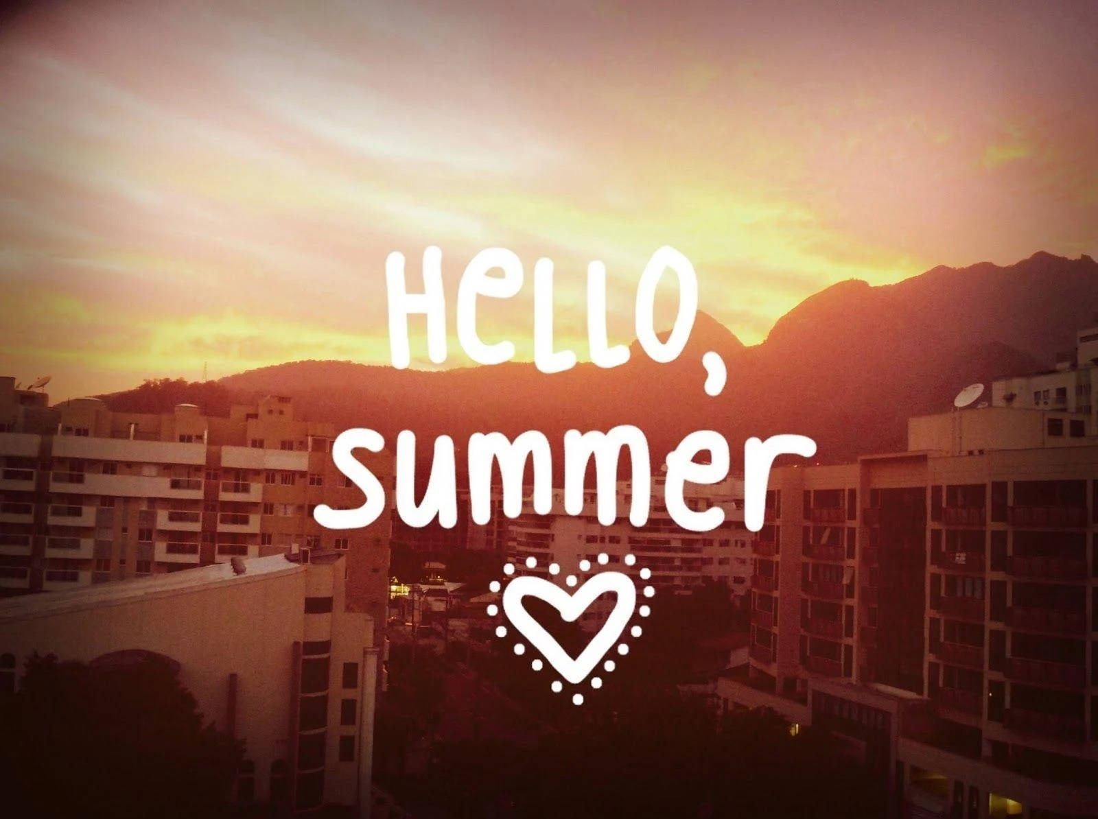 「Hello Summer」日落美學 壁紙 — 夕陽映照城市屋頂，背景有山巒，並覆蓋 'hello summer' 文字。