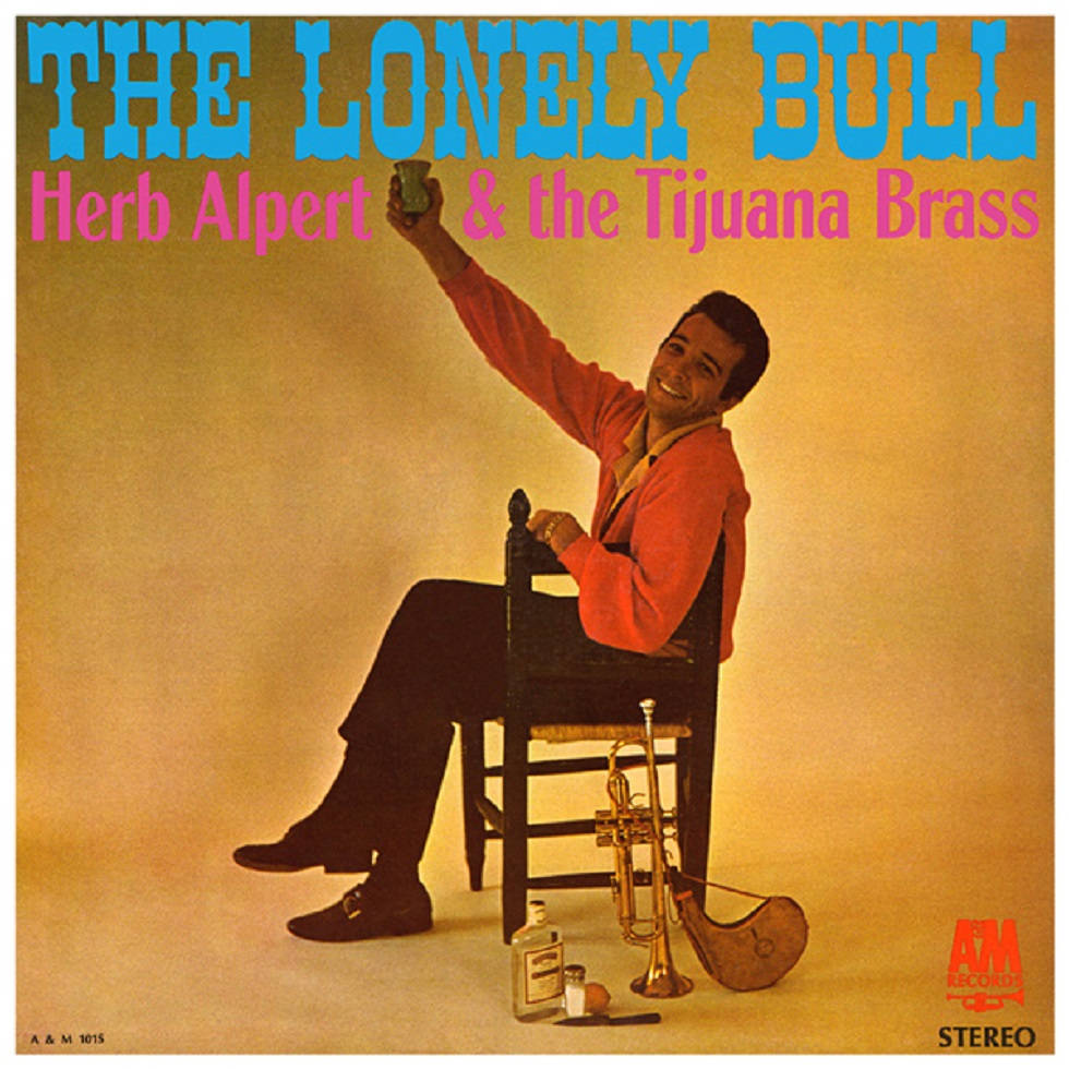 Herb Alpert 與 The Tijuana Brass《The Lonely Bull》專輯封面 壁紙 — 一個微笑的男人穿著紅色外套坐在椅子上，拿著一個杯子，旁邊有喇叭和瓶子，背景是溫暖的黃色。