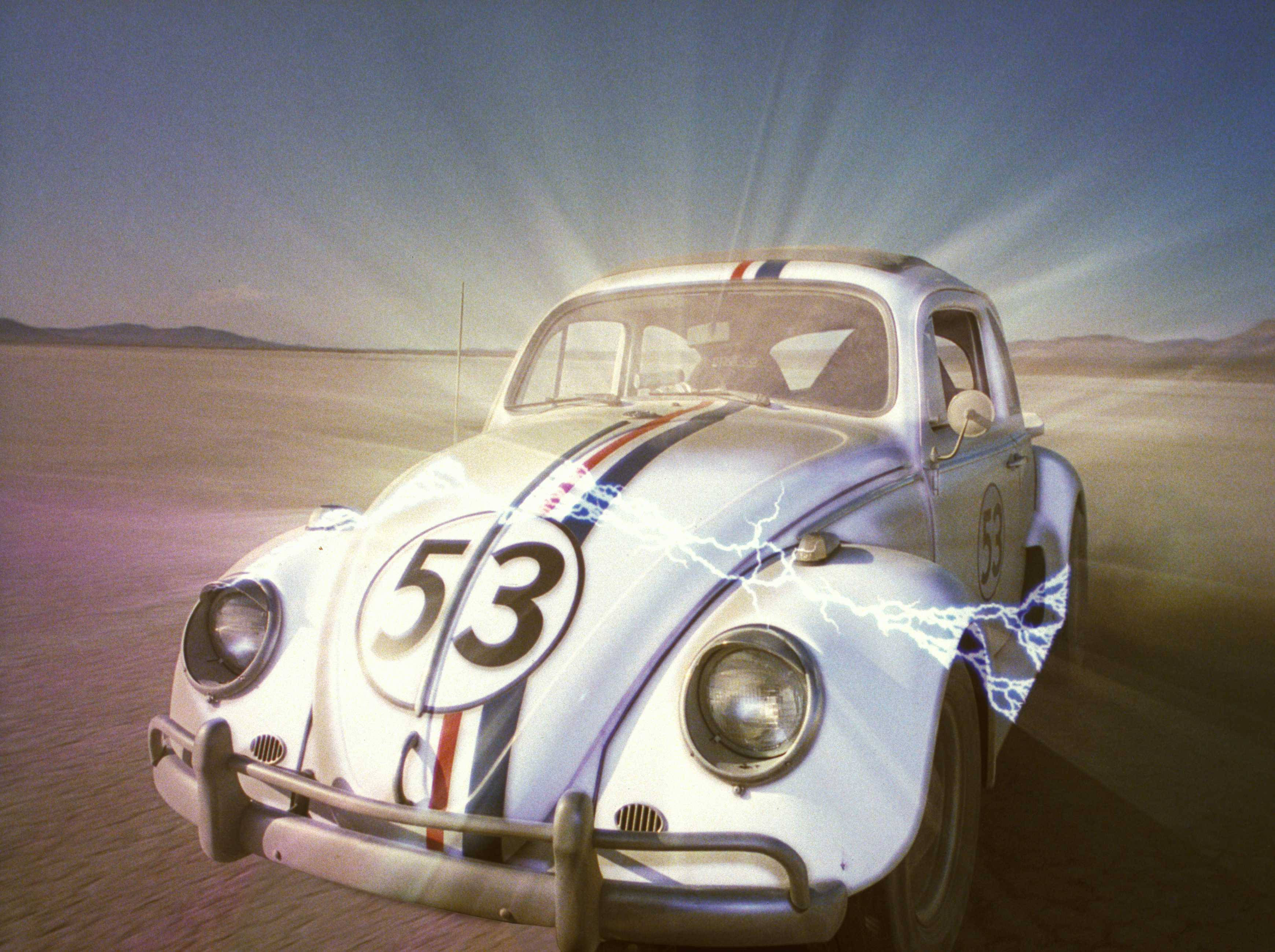 《Herbie：Fully Loaded》Herbie沙漠中發光 壁紙 — 一輛白色賽車改裝福士甲蟲車（編號53）在電光閃爍的烈日下飛馳過沙漠。