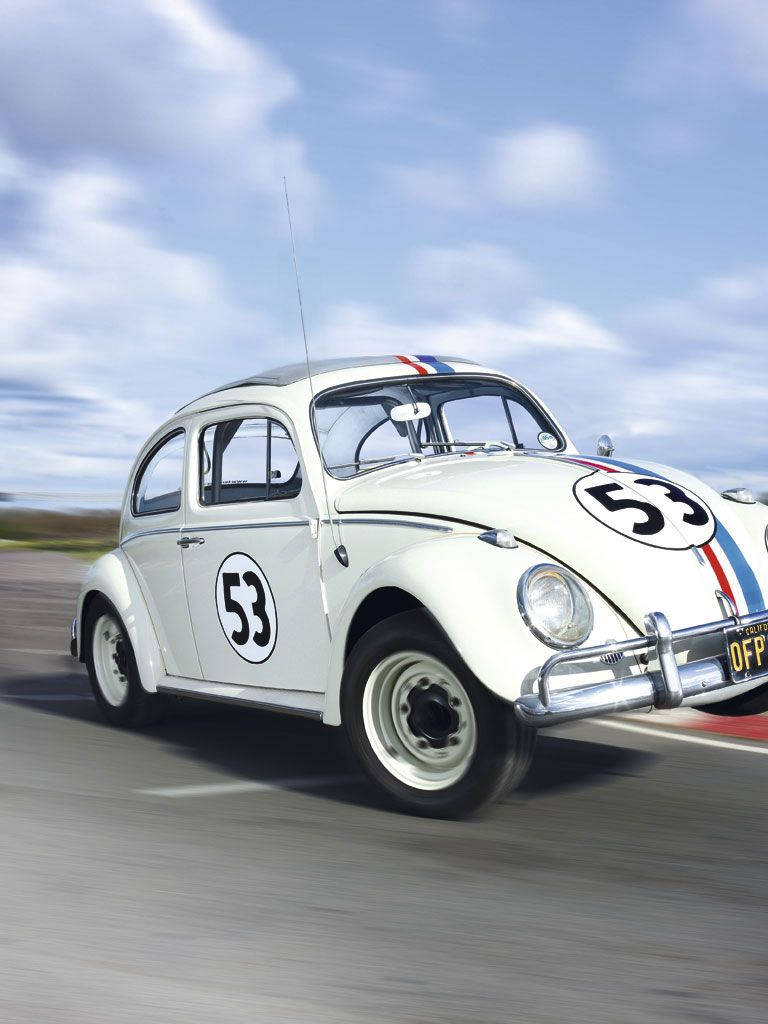 《Herbie：Fully Loaded》賽道飛馳壁紙 壁紙 — 一架白色復古賽車，編號53，在晴朗藍天和 fluffy 雲朵下沿著道路疾馳。