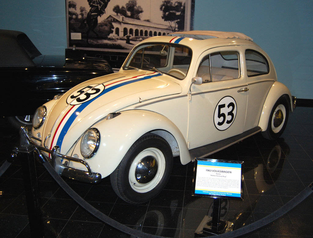 《Herbie：Fully Loaded》Herbie汽車展覽展示 壁紙 — 一輛純白色的1963年福士甲蟲賽車，帶有藍紅條紋和53號碼，在博物館的反射地板上展出。