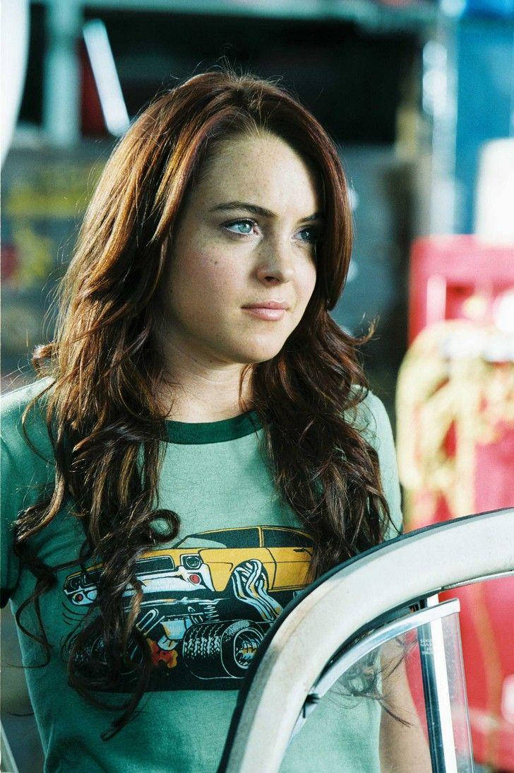 《Herbie Fully Loaded》琳賽·蘿涵綠色上衣 壁紙 — 一位長著棕色長髮和藍色眼睛的年輕女性，穿著帶有黃色汽車圖案的綠色T恤，若有所思地凝視著。