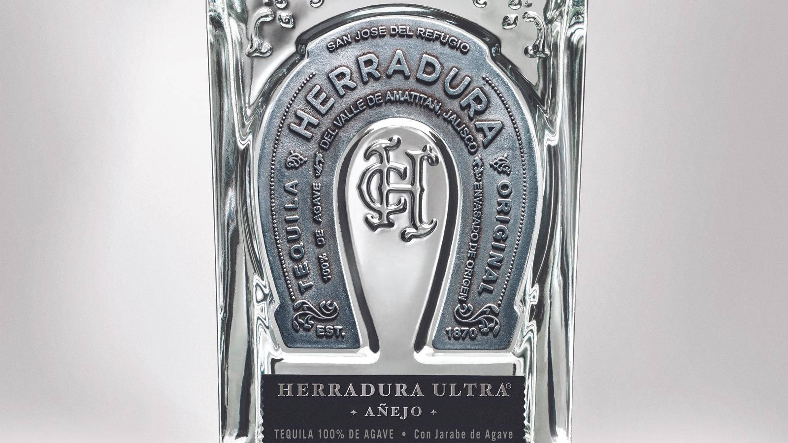 Herradura Ultra Añejo 龍舌蘭酒瓶的特寫，帶有銀色馬蹄鐵標誌。