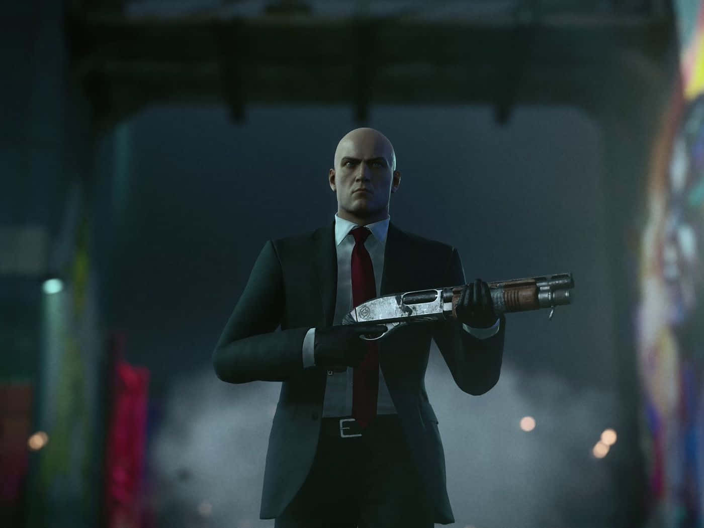 《Hitman 2》中的爆炸性動作場景。 壁紙 — 一個光頭男人穿著黑色西裝和紅色領帶，在昏暗的城市拱門下拿著一把霰彈槍，背景有模糊的彩色燈光。