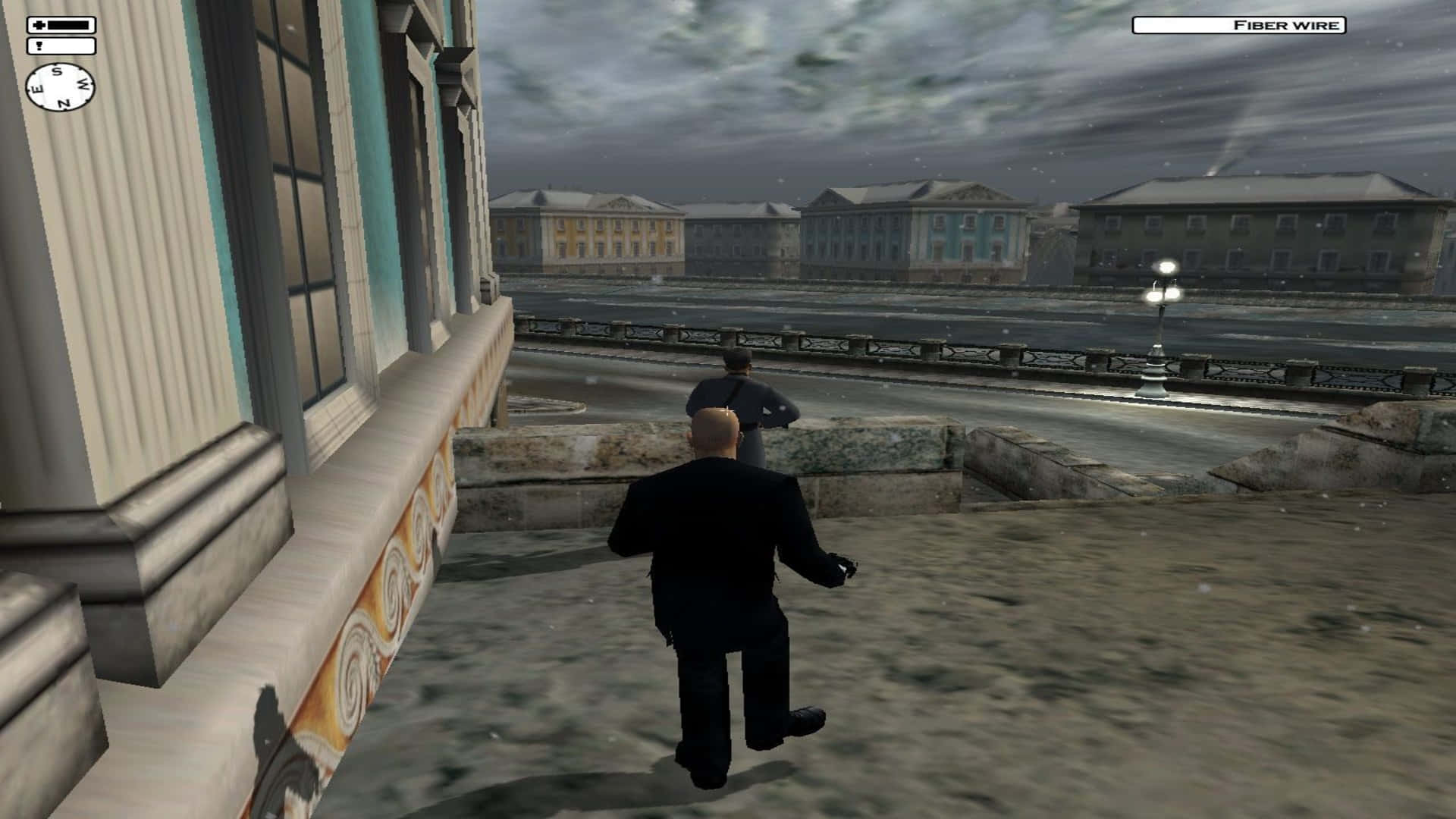 《Hitman 2》高清背景：特工潛行暗殺 壁紙 — 一個光頭男人穿著黑色西裝，在潮濕的石頭廣場上跑向另一個人物，天空灰暗風暴。