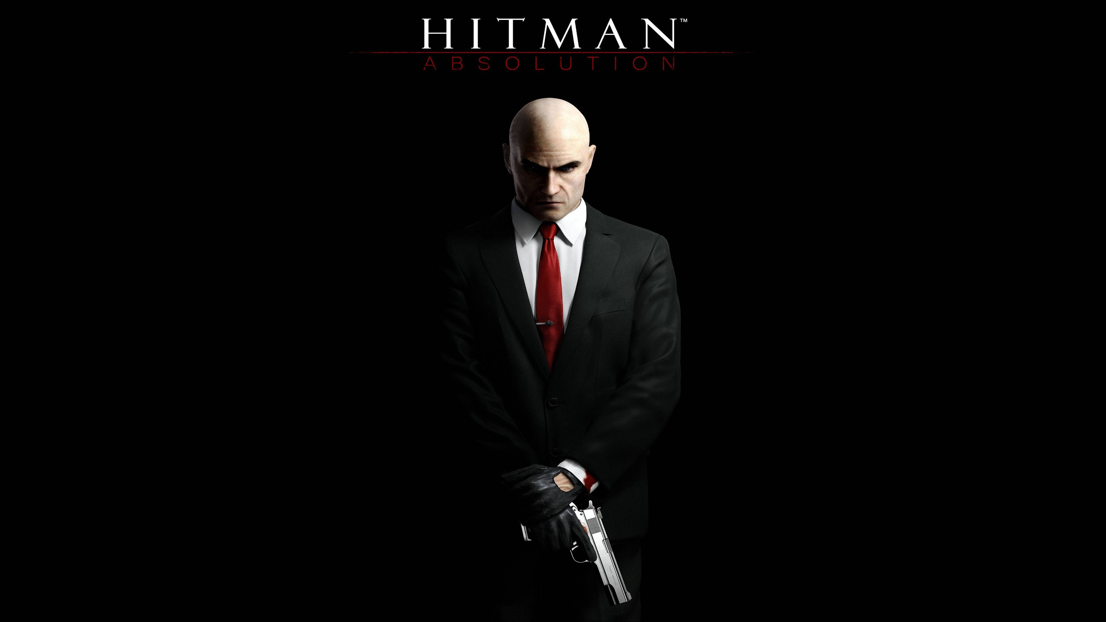 《Hitman Absolution》黑色刺客裝特工47 壁紙 — 一個光頭男人穿著黑色西裝和紅色領帶，手持銀色手槍，背景為純黑色，上方有「Hitman Absolution」文字。