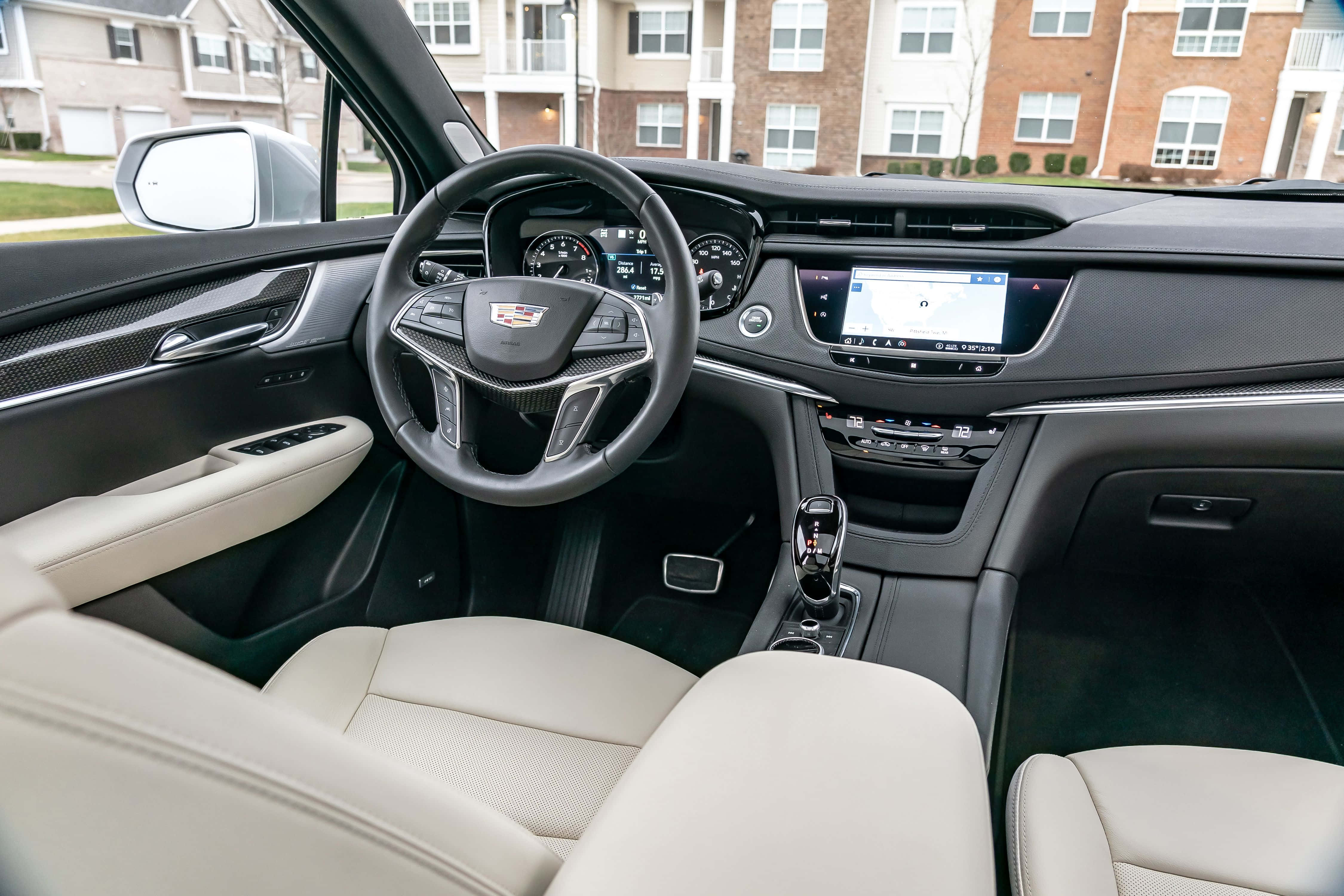 Cadillac Xt5 桌布 壁紙 — 豪華汽車內飾，配備奶油色皮革座椅和黑色儀表板，帶數碼顯示屏和方向盤。