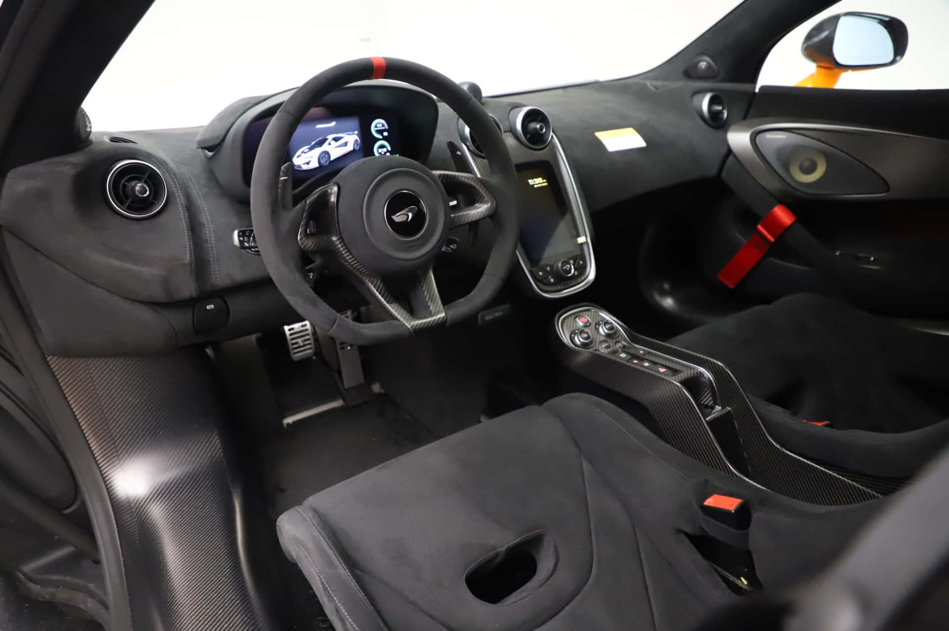Mclaren 620r 桌布 壁紙 — 豪華跑車內飾，帶有黑色碳纖維飾邊和紅色安全帶。