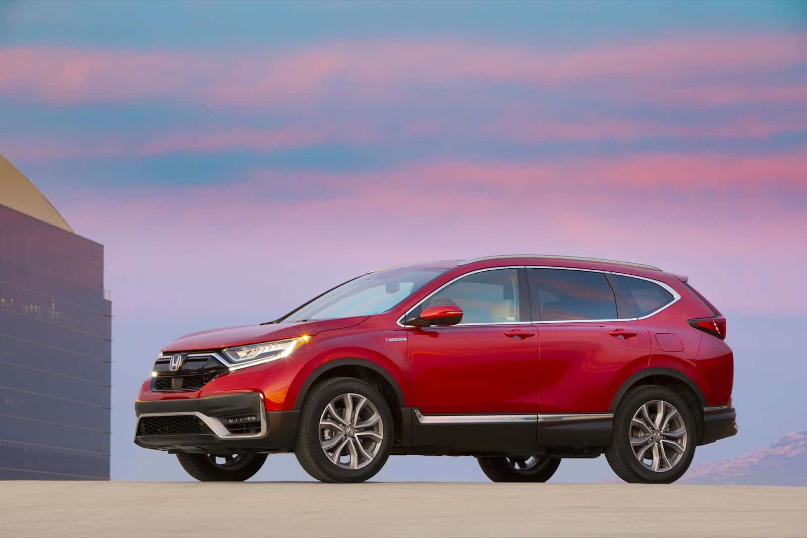 Honda Cr-v 桌布 壁紙 — 一輛鮮紅色的本田CR-V SUV停泊在混凝土表面上，背景是粉彩粉紅和藍色的暮色天空，以及現代建築。