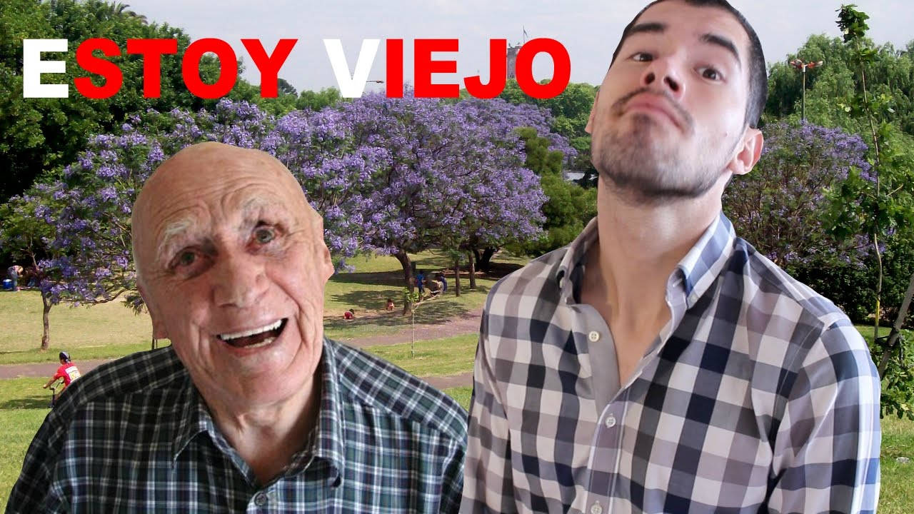 HolaSoyGerman「我老了」影片封面 壁紙 — 兩名穿著格仔恤衫嘅男人喺一個有紫色花樹嘅公園入面，喺晴朗嘅天空下擺甫士。