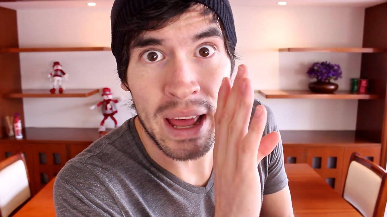 HolaSoyGerman 手掩口低語 壁紙 — 一個男人睜大眼睛、張開嘴巴，用手掩住臉頰，露出驚訝的表情，在室內。