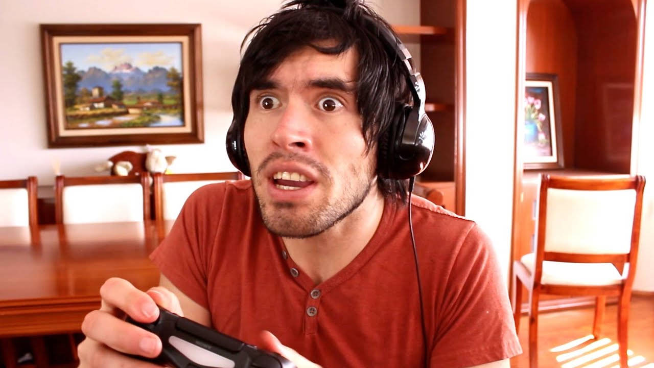 HolaSoyGerman 玩遊戲 壁紙 — 一個男人睜大眼睛張開嘴，戴著耳機，在陽光充足的飯廳裡緊握遊戲控制器。