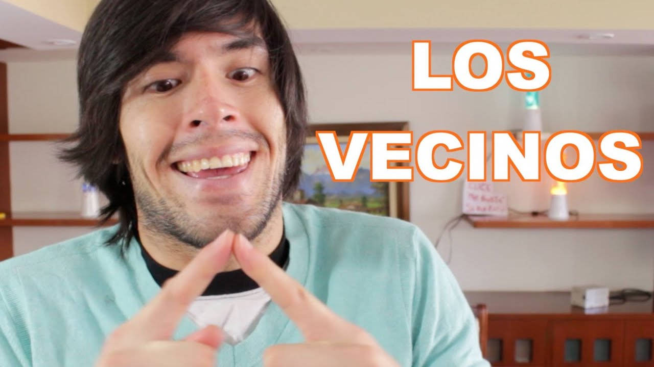 HolaSoyGerman 食指相碰搞笑 壁紙 — 一位黑髮的開朗男子在室內用手指形成三角形，露出燦爛的笑容。