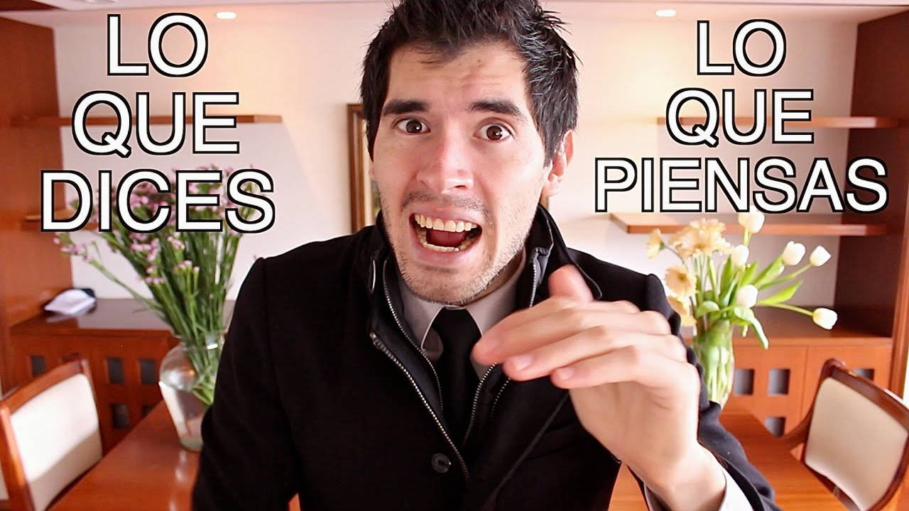 HolaSoyGerman 黑色大衣 壁紙 — 一名身穿黑色外套的男子在溫暖照明的飯廳中，誇張地表現出震驚的反應，同時指向鏡頭。