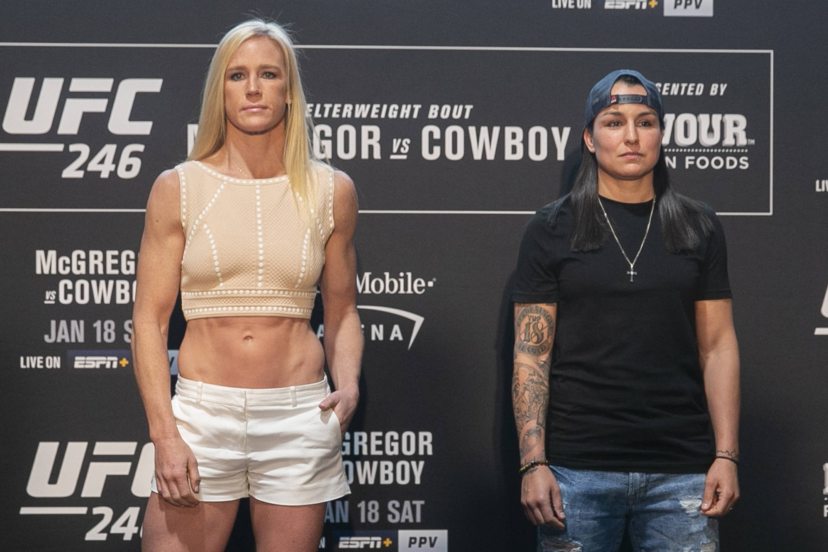 Holly Holm與Racquel Pennington 壁紙 — 兩位女性UFC拳手在記者會上準備就緒，身後有宣傳橫幅。