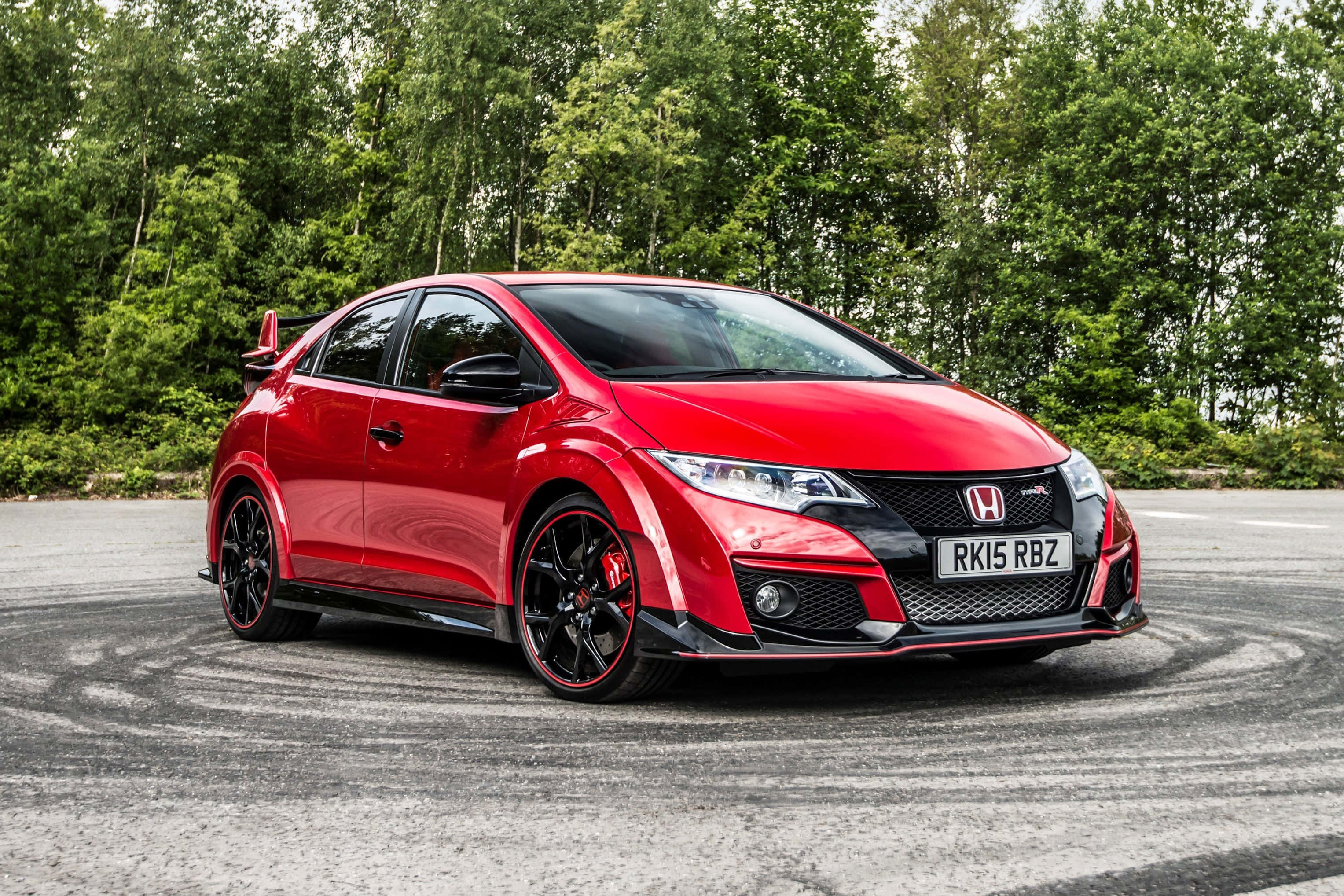 與 Honda Civic Type R 一同體驗極速駕馭 壁紙 — 一輛充滿活力的紅色本田思域Type R在鋪砌的場地上飄移，周圍環繞著茂密的綠樹。