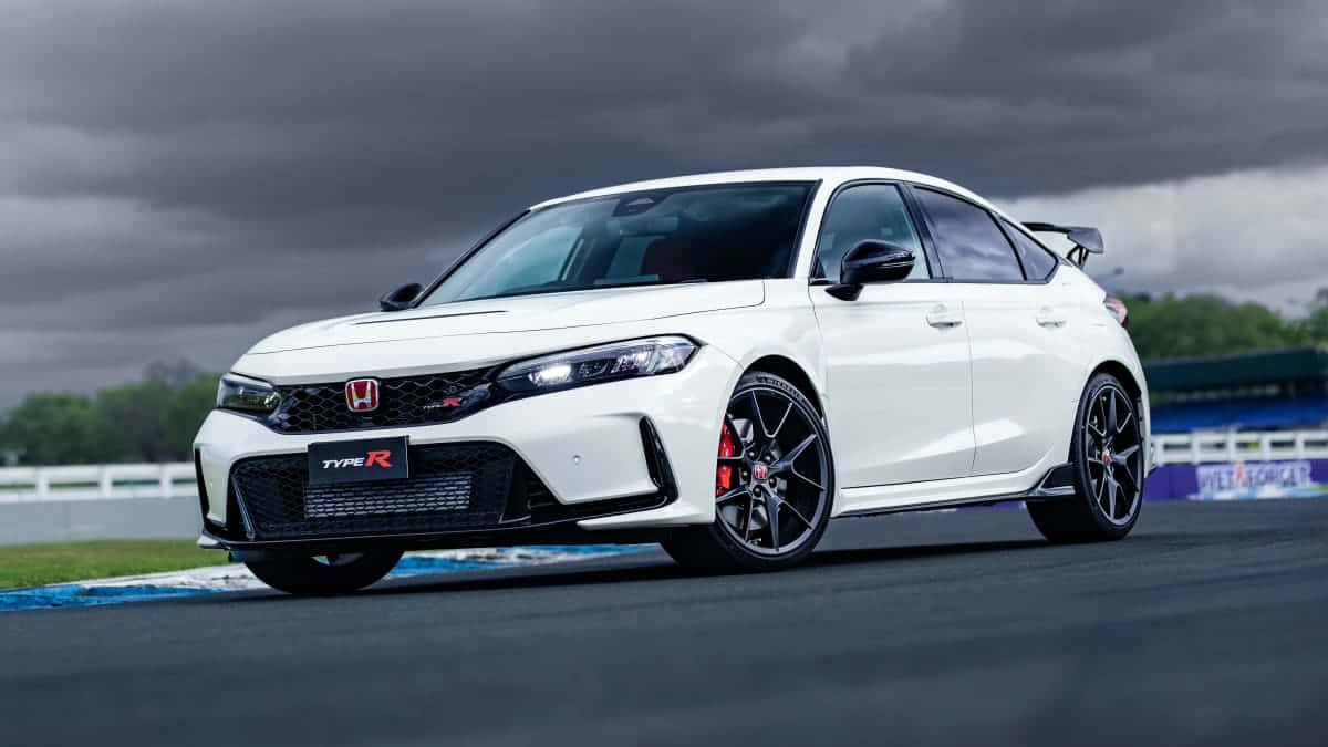 體驗極致駕馭快感：Honda Civic Type R 壁紙 — 一輛白色本田 Type R 跑車，配備黑色輪圈和紅色制動卡鉗，在暴風雨天空下的賽道上蓄勢待發。