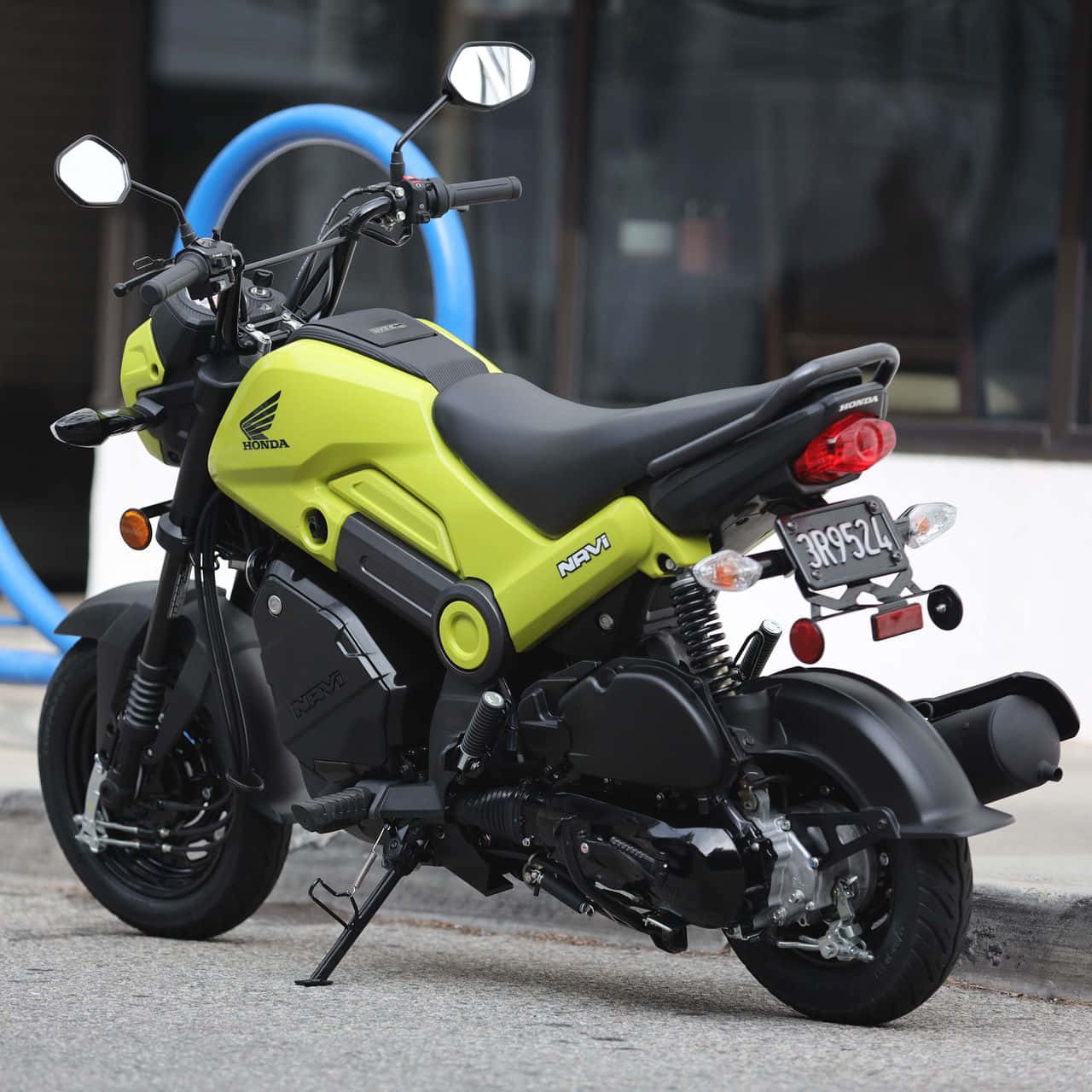 黑與霓虹綠Honda Navi踏板車 壁紙 — 一輛明亮的青檸綠色本田 Navi 電單車停泊在人行道上，帶有黑色飾邊和鍍鉻細節。