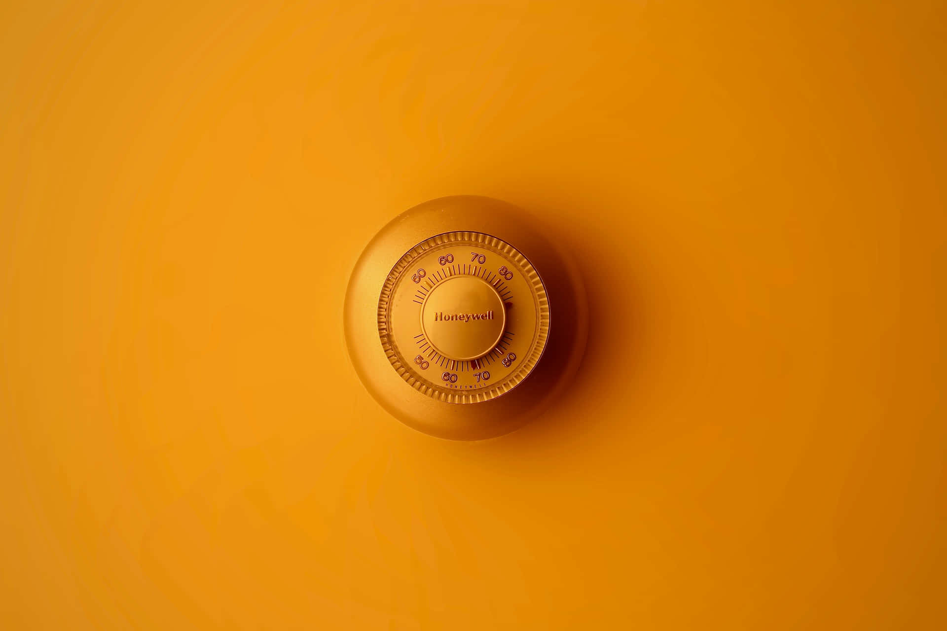 一個Honeywell恆溫器對著純橙色牆壁。