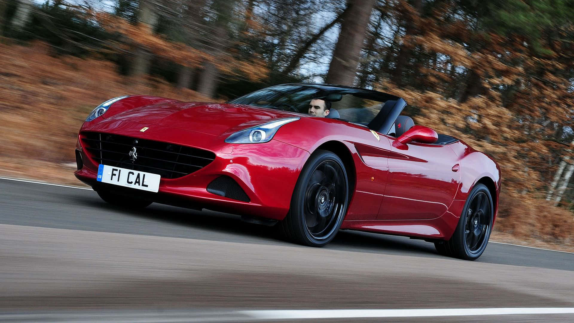 Ferrari California T 桌布 壁紙 — 一輛充滿活力的紅色法拉利加利福尼亞開篷跑車沿著森林道路奔馳，動態模糊強調其動感。