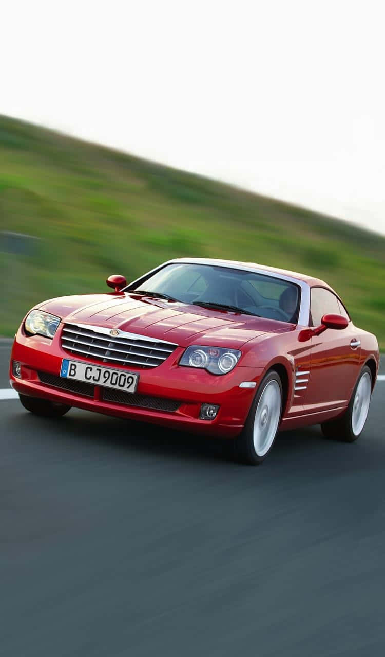 Chrysler Crossfire 桌布 壁紙 — 一輛充滿活力的紅色開篷跑車在蜿蜒的道路上飛馳，背景是模糊的綠色山丘。