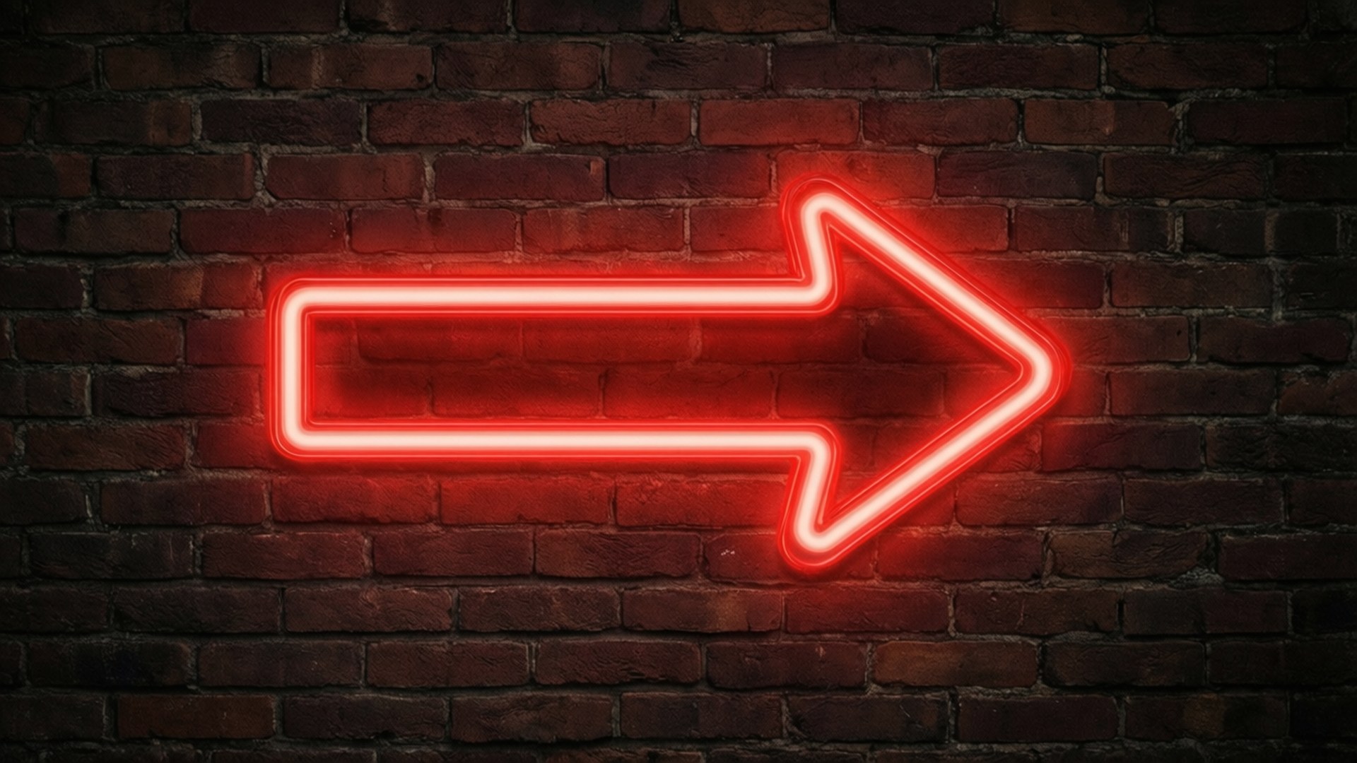Neon Arrow 壁紙 — 一個發光的紅色霓虹箭頭標誌安裝在深色紋理磚牆上，散發出溫暖的光芒。