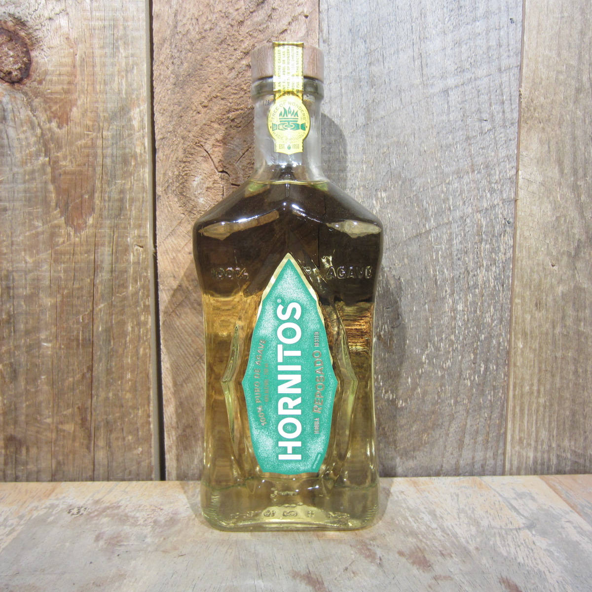 一個Hornitos龍舌蘭酒樽喺木質表面同木質背景上。