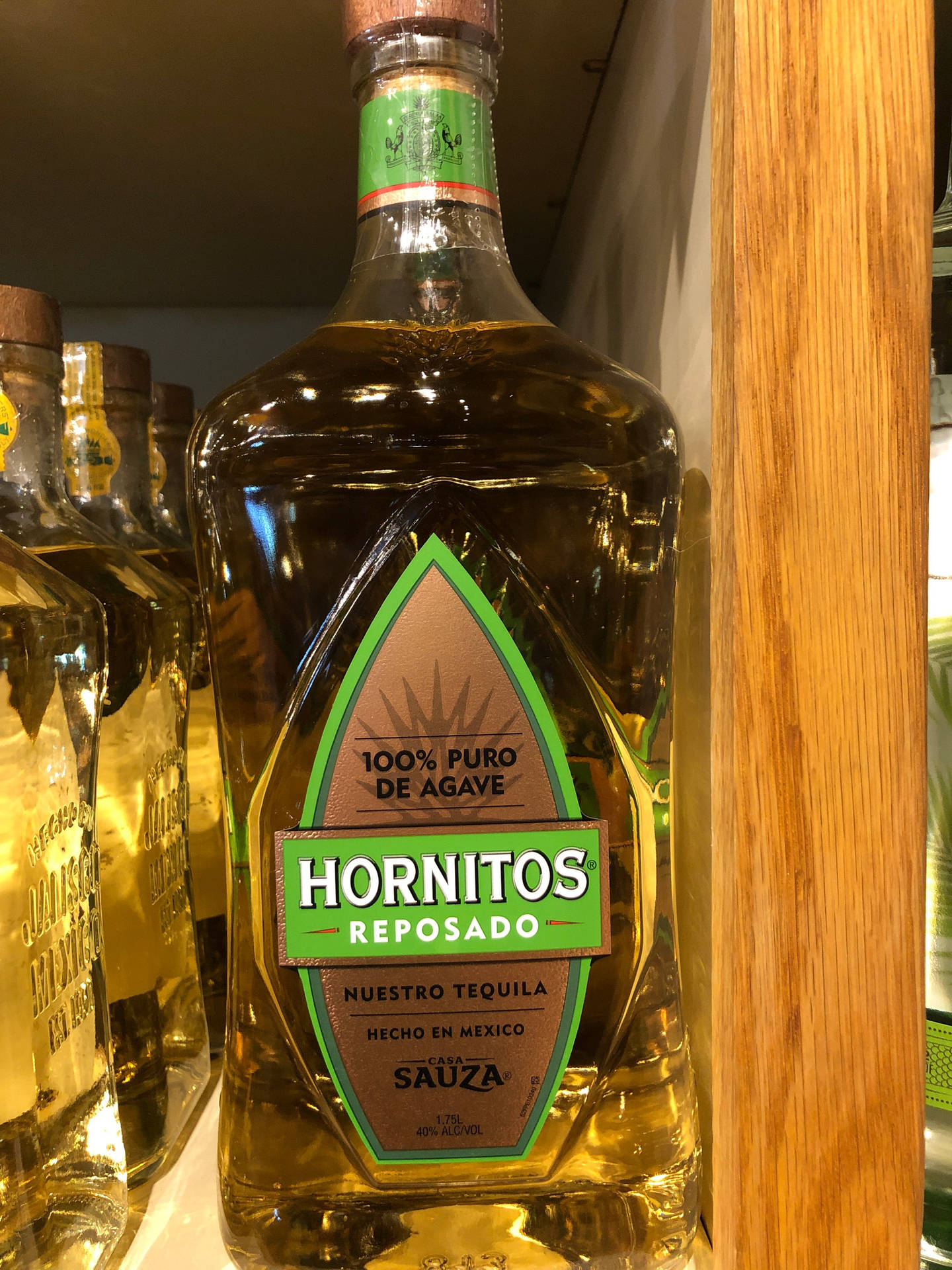 木鑲板旁邊商店架上嘅一瓶Hornitos Reposado龍舌蘭酒。
