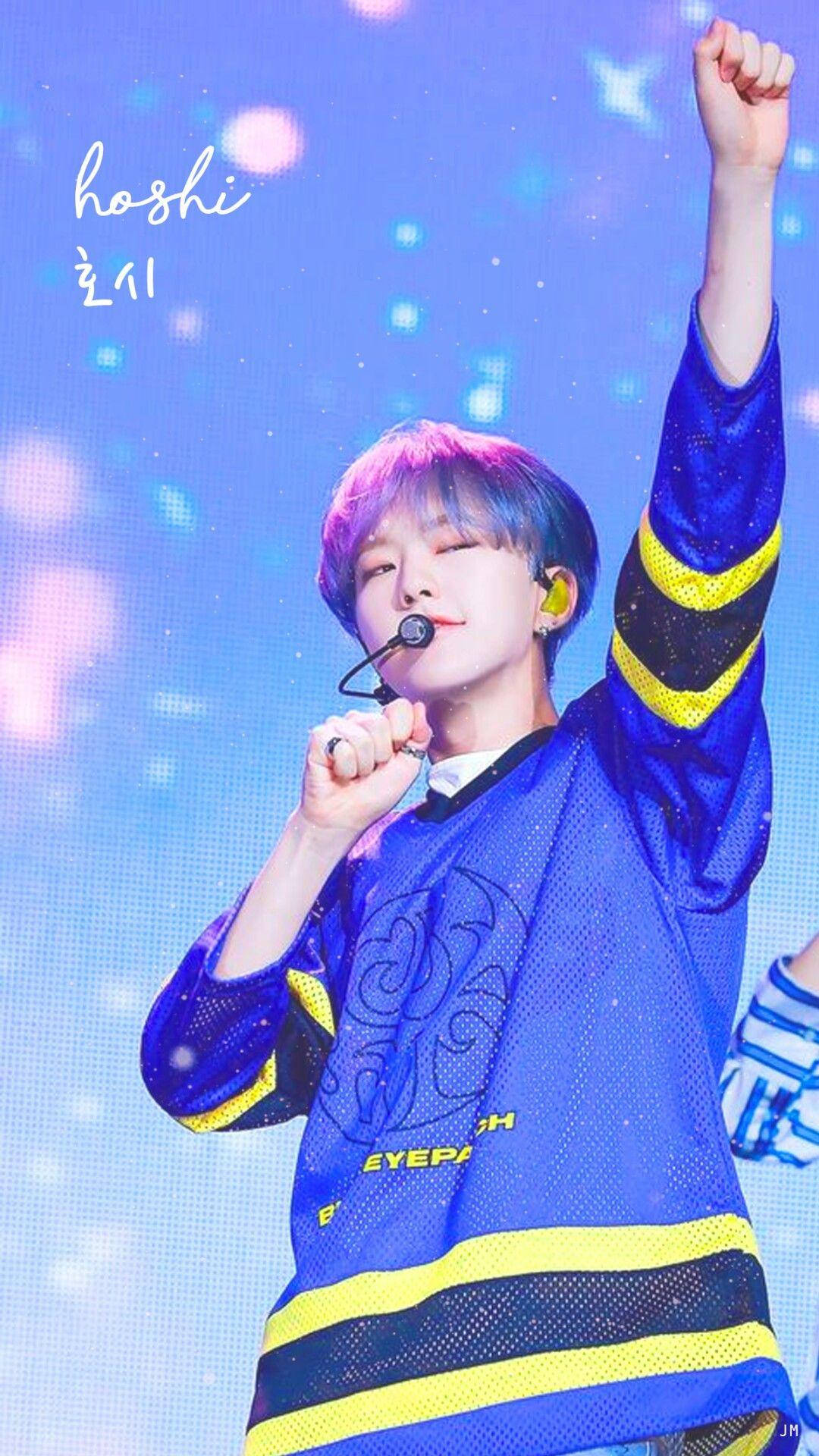 Hoshi 舞台演出 壁紙 — 一位紫髮年輕表演者在閃爍燈光下，身穿藍黃球衣在舞台上唱歌。
