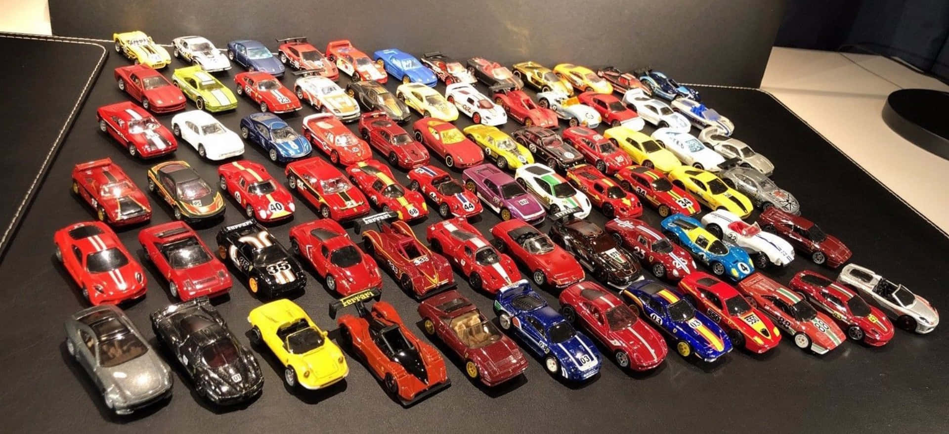 在深色桌子上排列成行的色彩繽紛玩具車的大型展示。