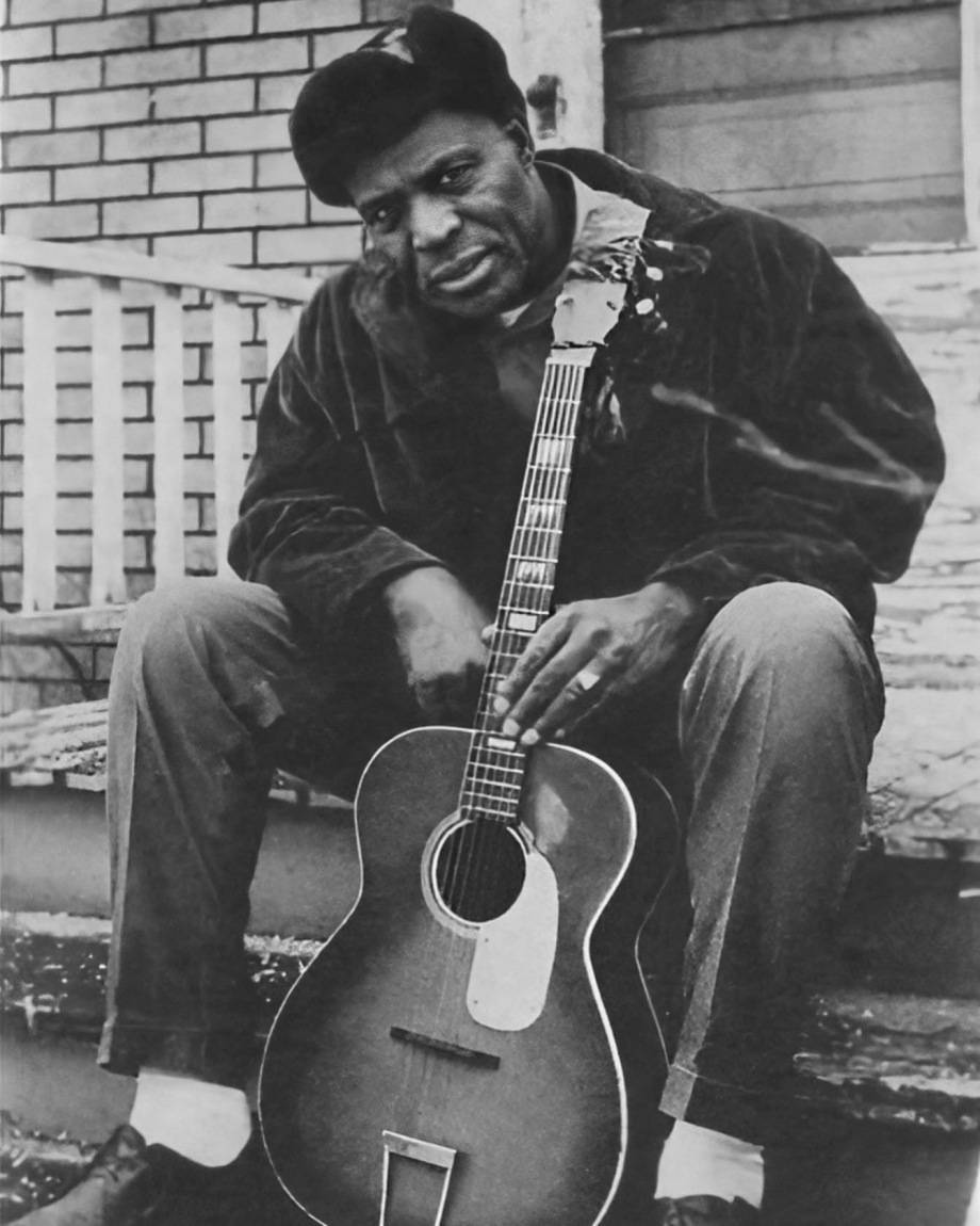 Howlin' Wolf 藍調歌手海報照片 壁紙 — 一位戴貝雷帽的男子坐在門廊階梯上抱著木結他的黑白肖像。