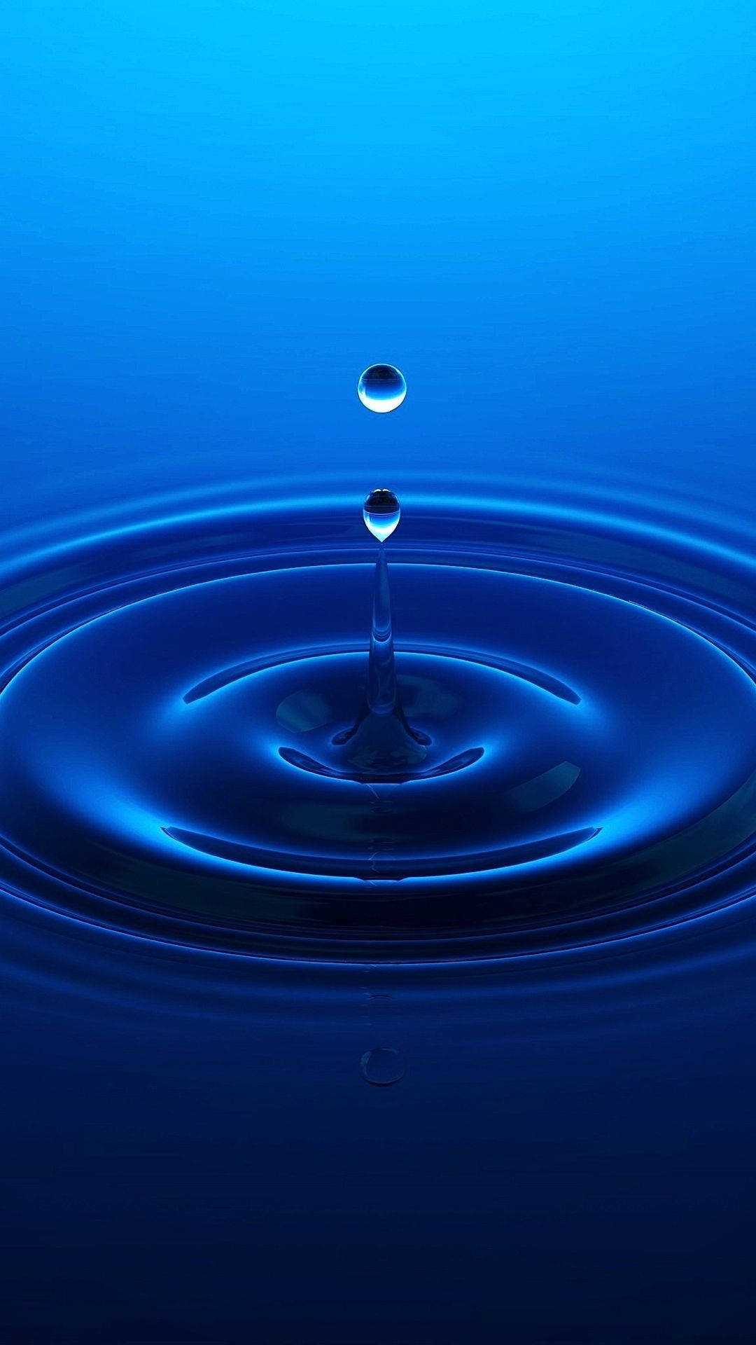 水滴懸浮在水面上，在深藍色液體中產生漣漪。