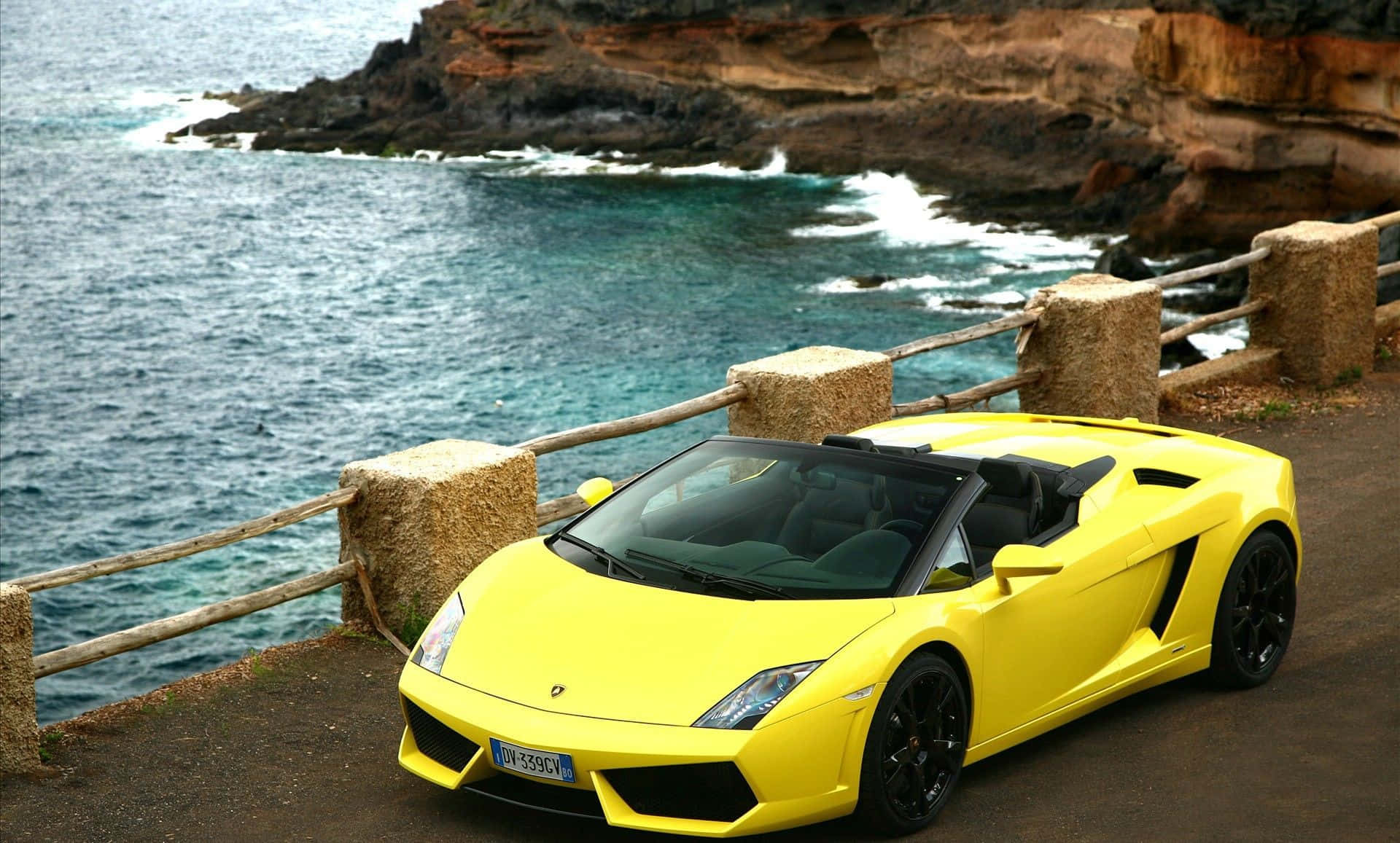 Lamborghini Murciélago 桌布 壁紙 — 一架亮黃色的林寶堅尼Gallardo Spyder停泊在海岸懸崖上，俯瞰著碧綠色的海浪。
